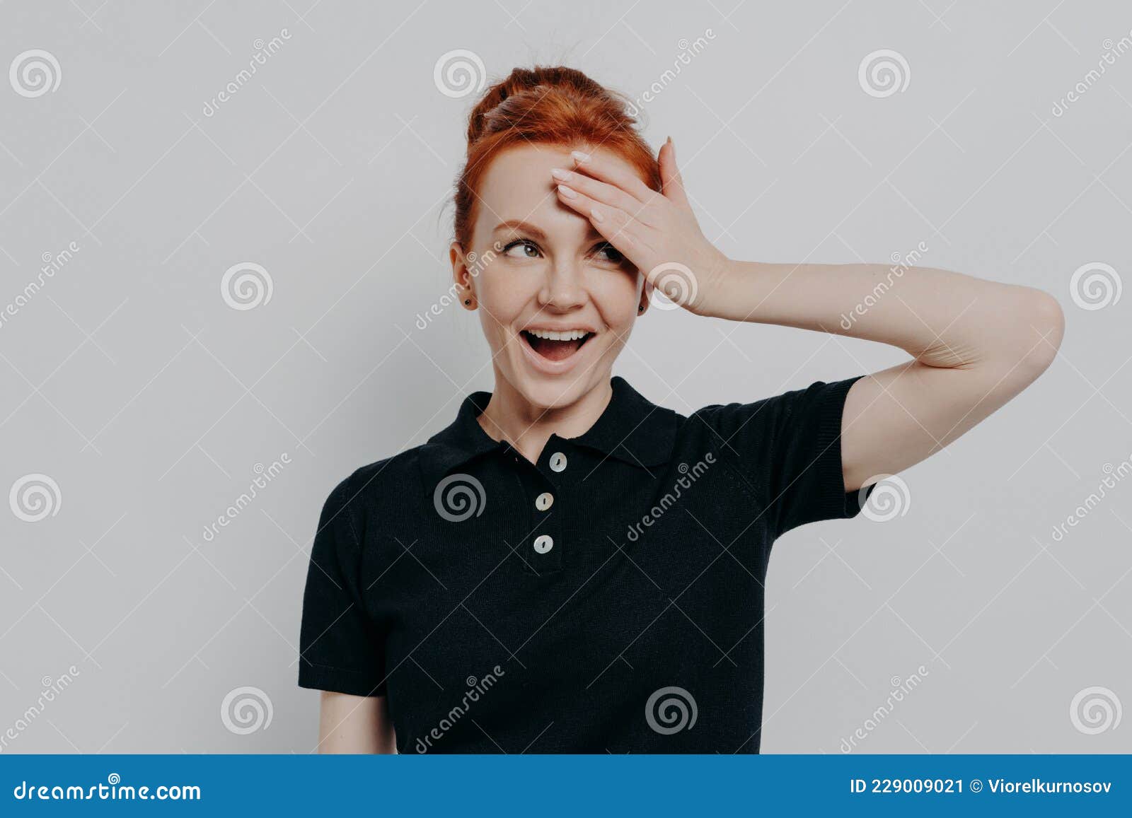 Happy Young Redhead Woman With Opened Mouth Touching Her Forehead With