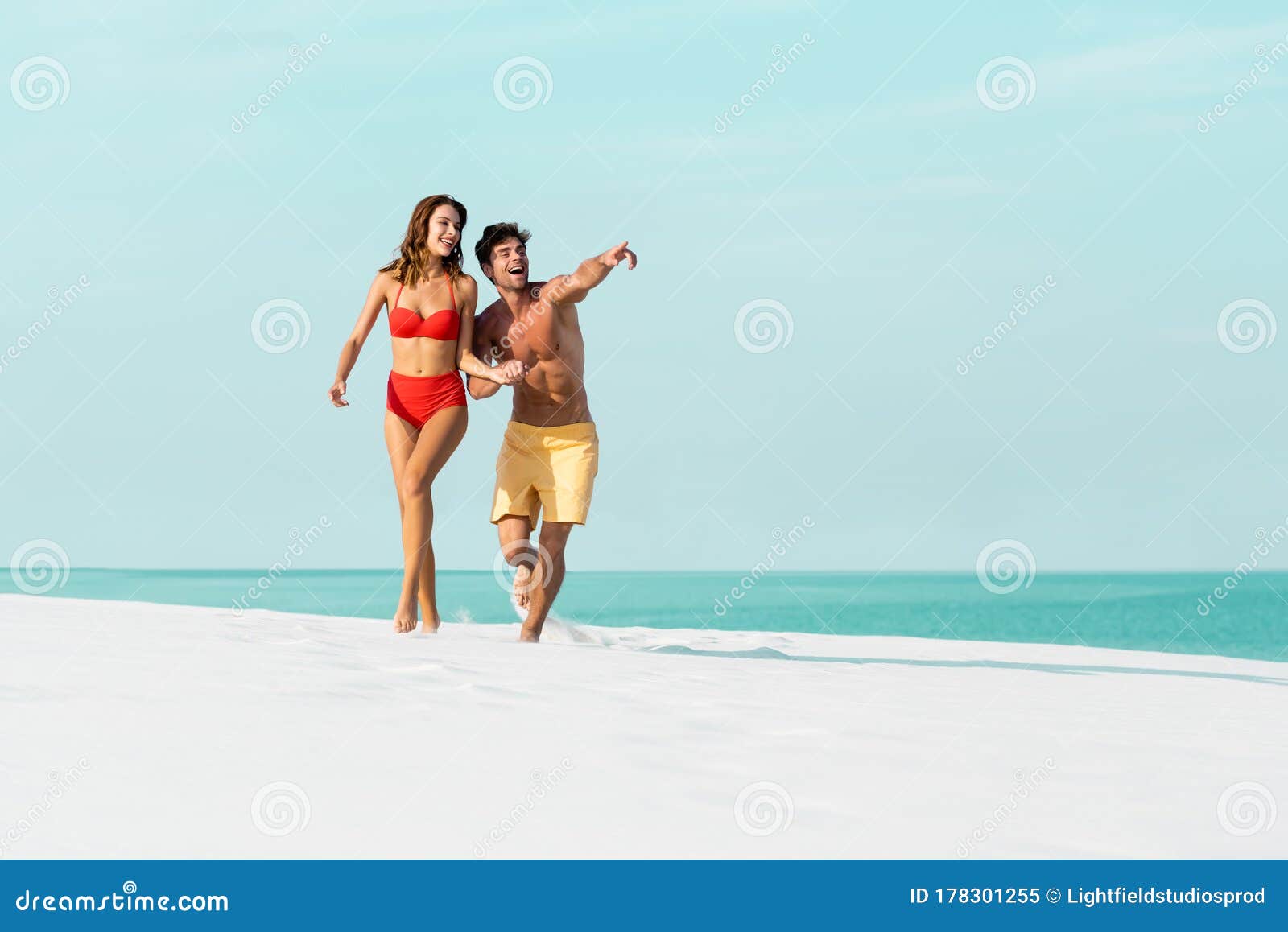 Cheerful couple having some good time naked on the beach