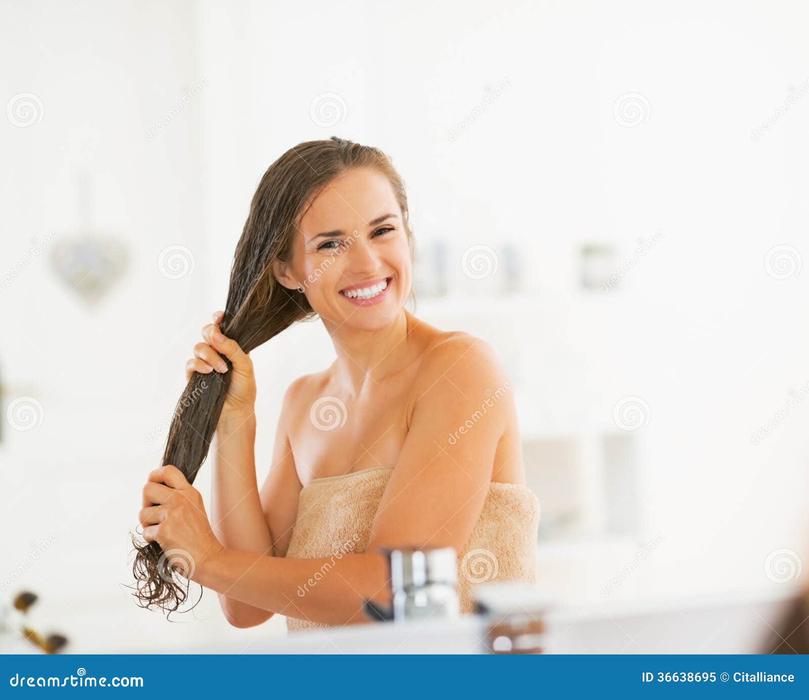 happy young woman applying hair mask in bathroom