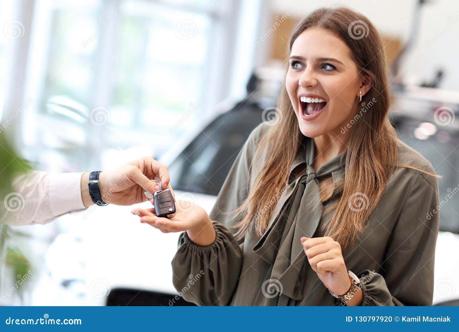 happy young woman buying car in showroom