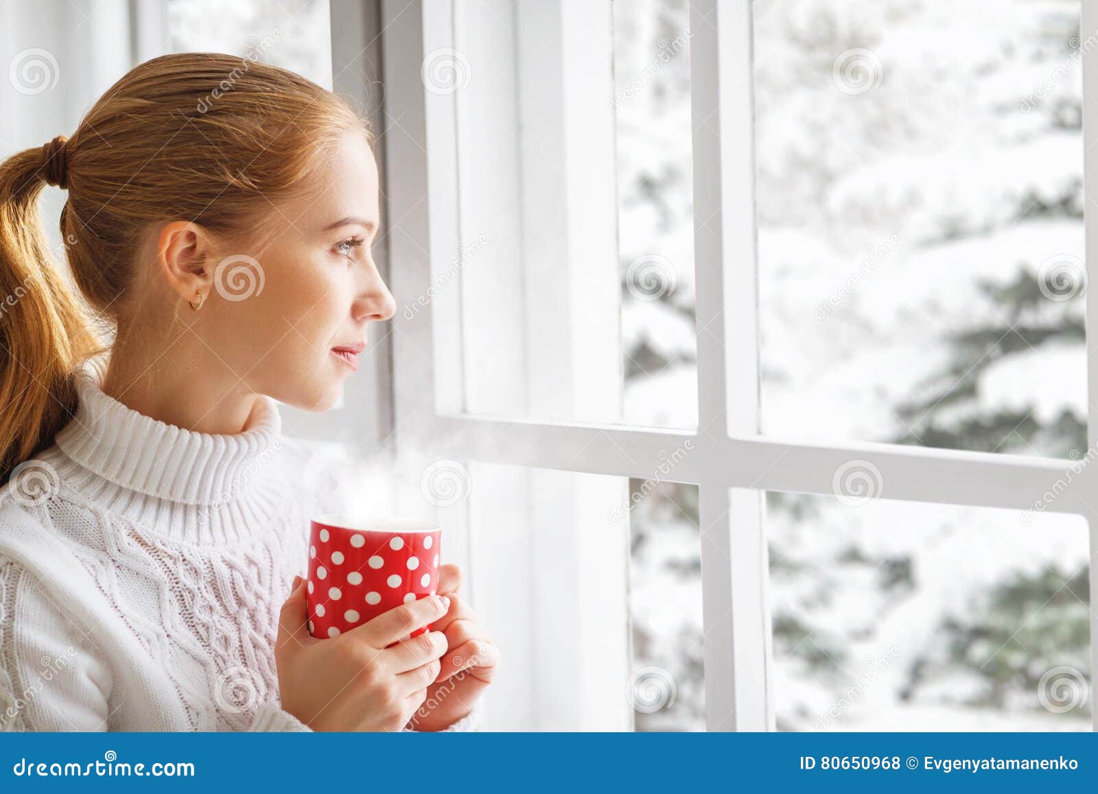 happy young woman with cup of hot tea in winter window christmas