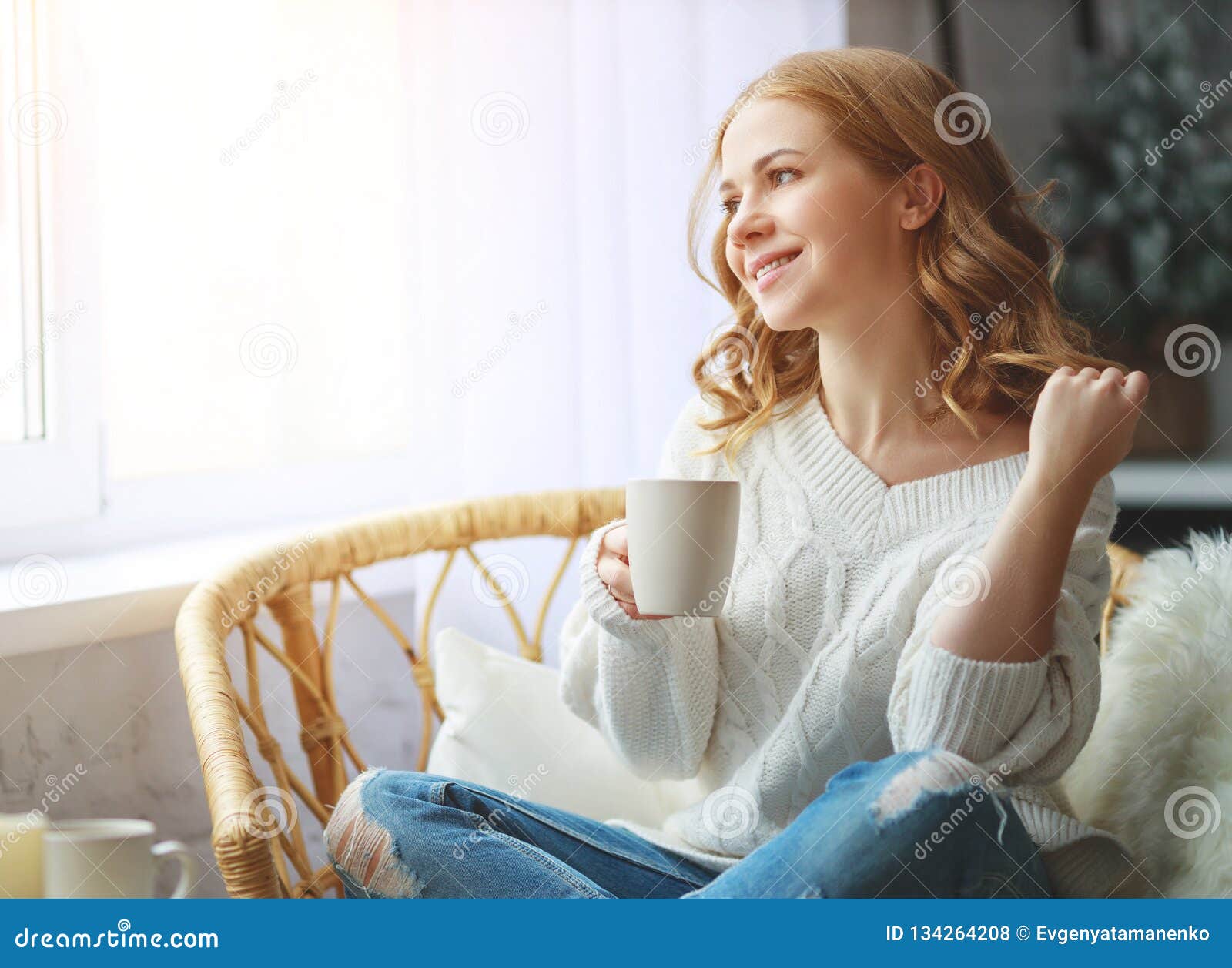 happy young woman drinking morning coffee by window in winter