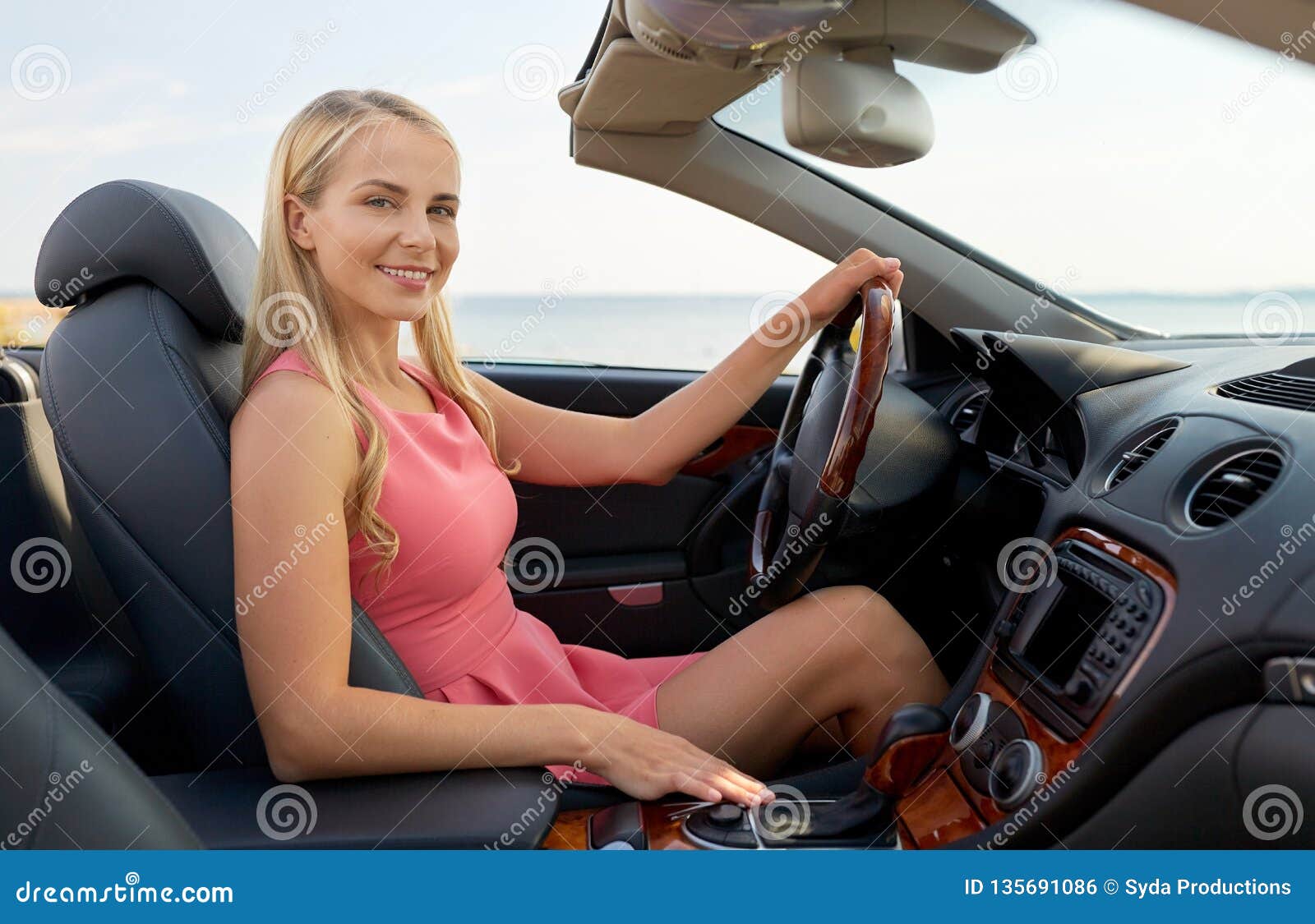 Happy blonde woman with flowing hair waving in a convertible - wide 7