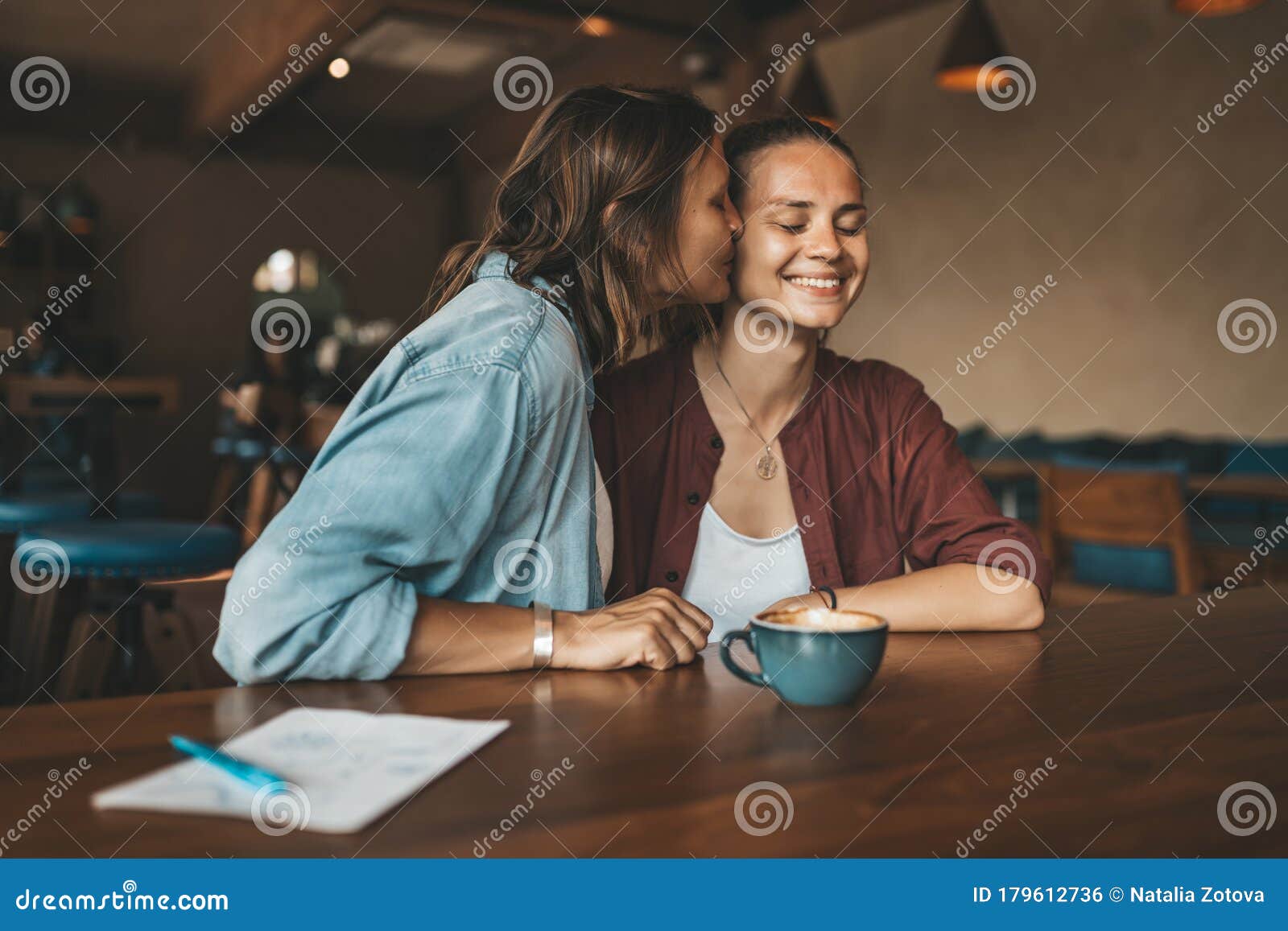 Happy Young Woman Kissing Her Girlfriend Sitting In A Cafe Stock P