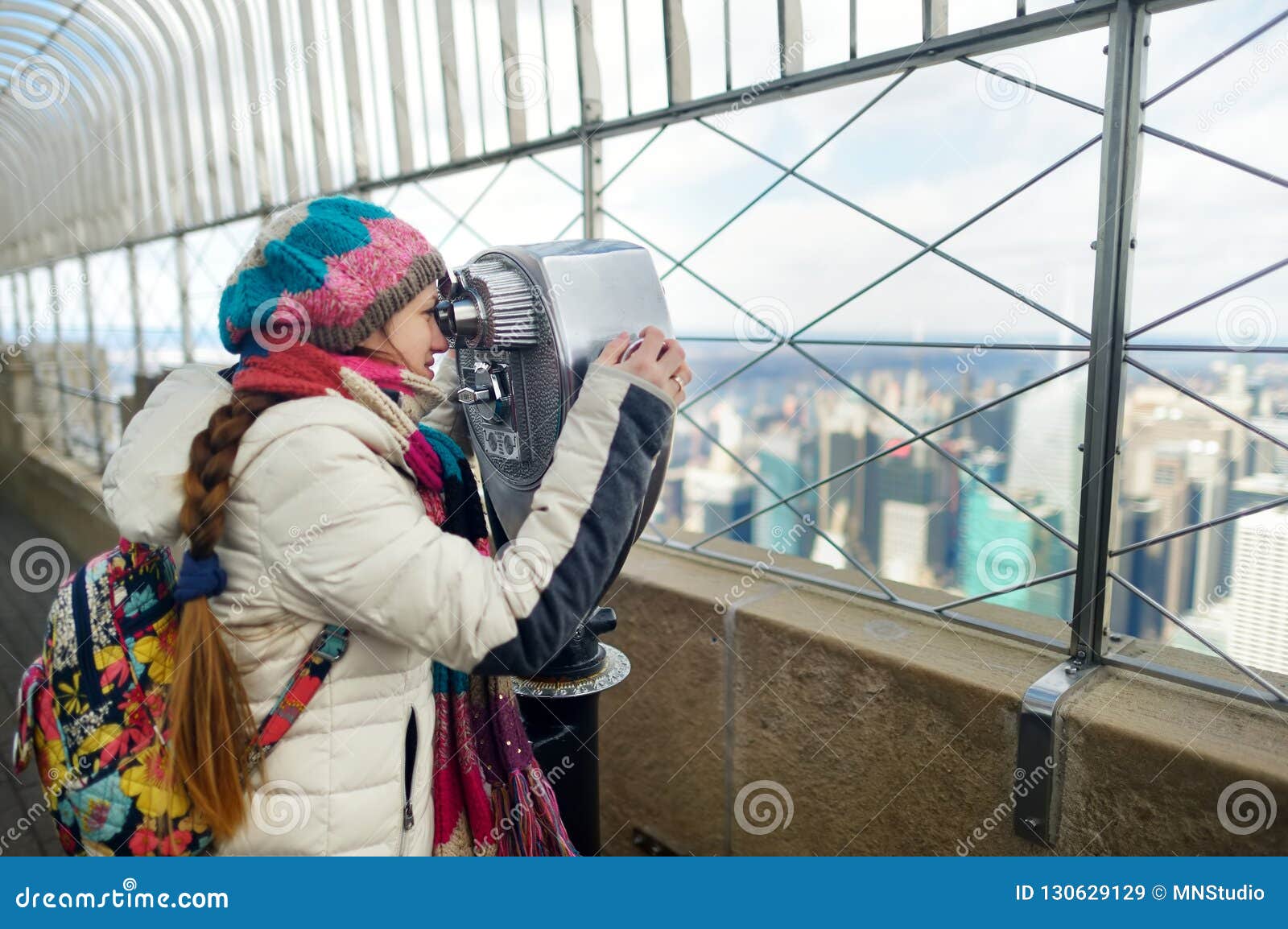 happy young woman tourist at the observation deck of empire state building in new york city. female traveler enjoying the view of