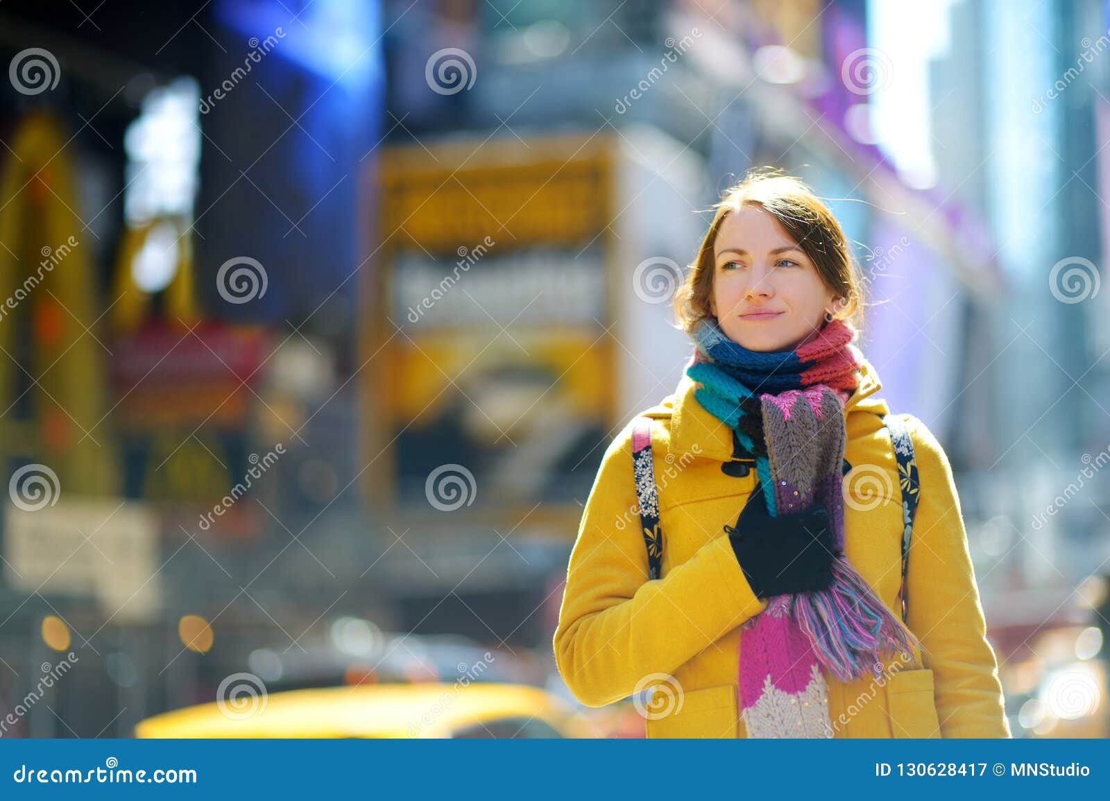 happy young woman tourist sightseeing at times square in new york city. female traveler enjoying view of downtown manhattan.