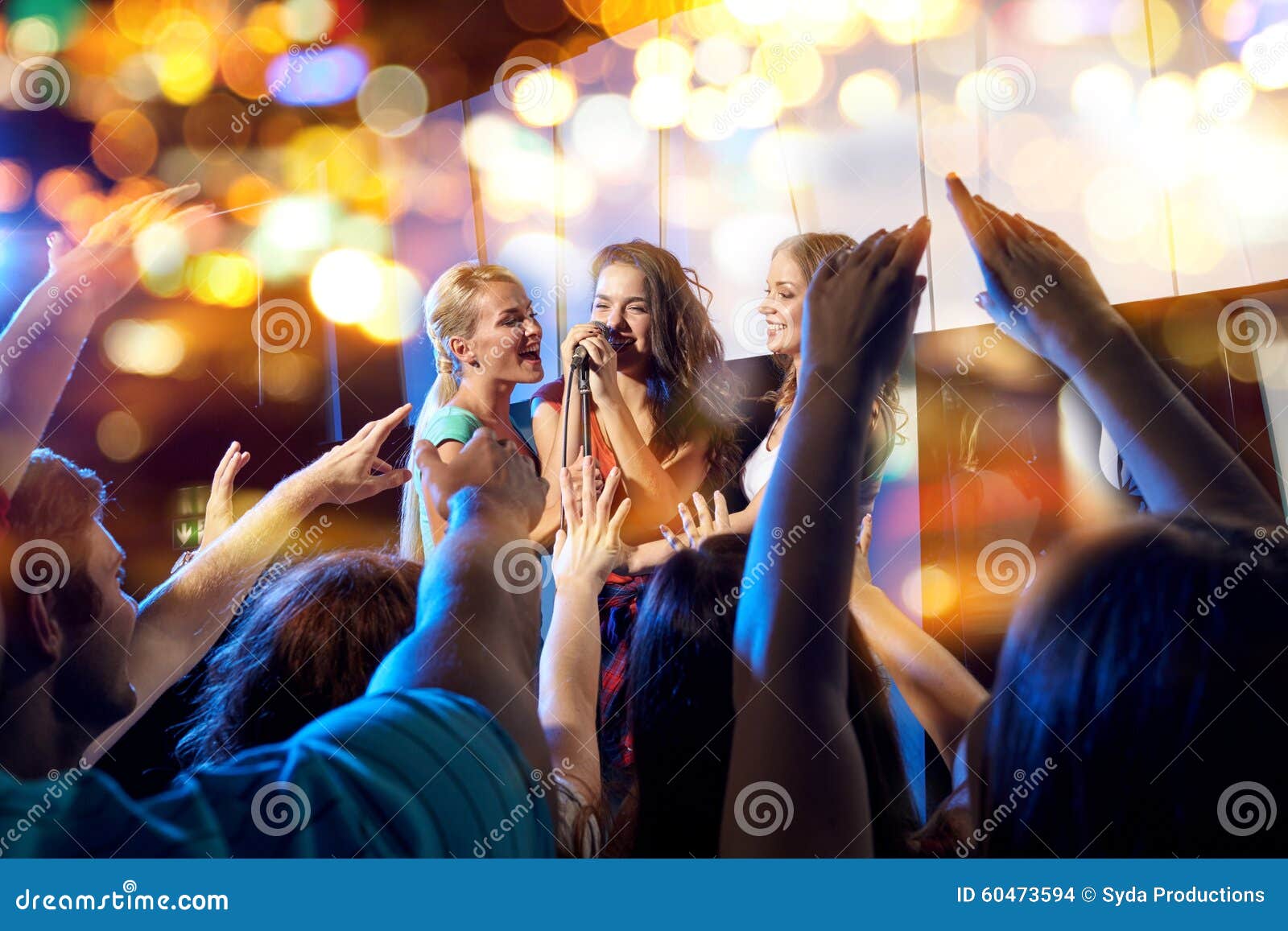 happy young women singing karaoke in night club