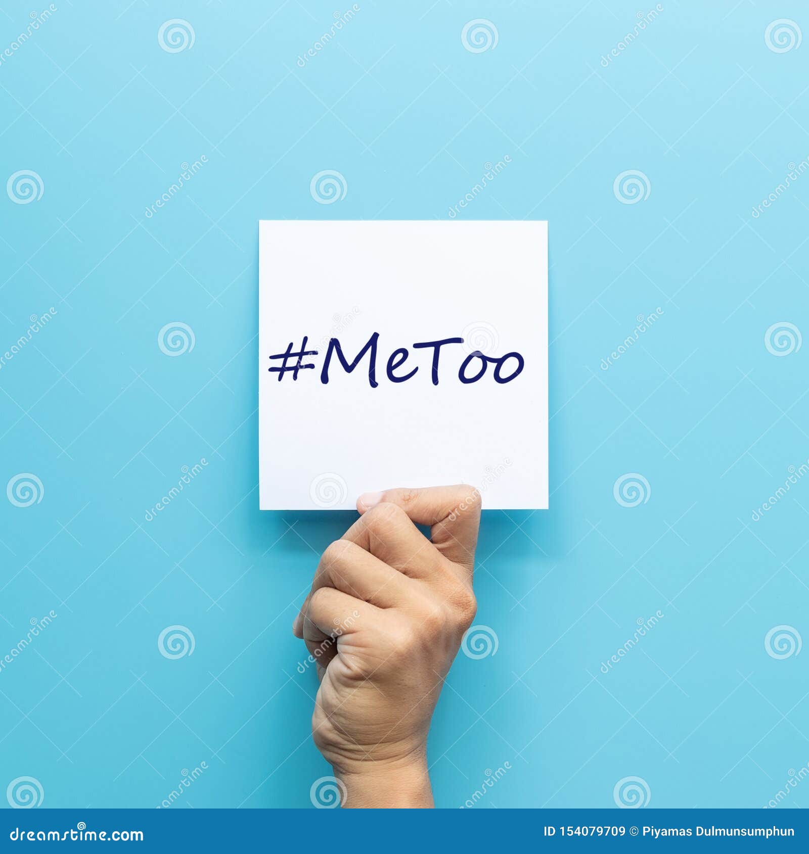 hashtag  metoo on white paper in hand  on blue background.  metoo is a campaign for movement against sexual harassment