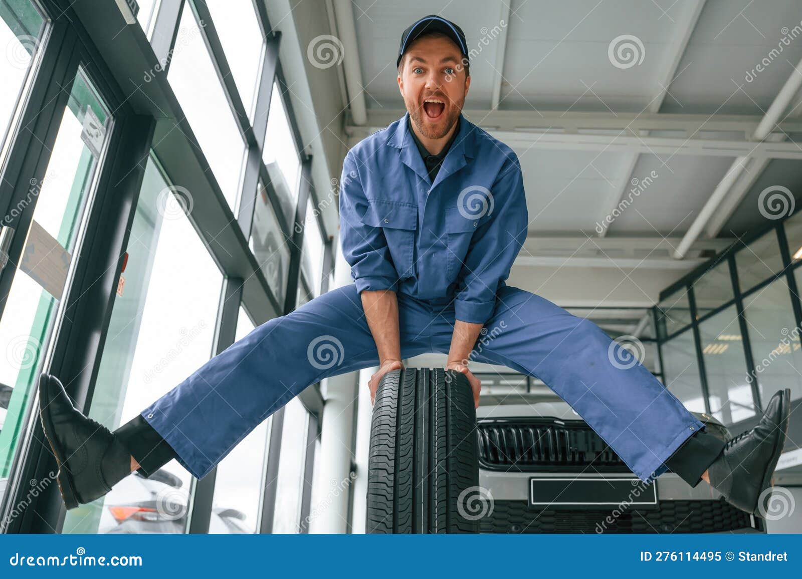 Having Fun, Smiling, with Tire. Man in Blue Uniform is Working in the