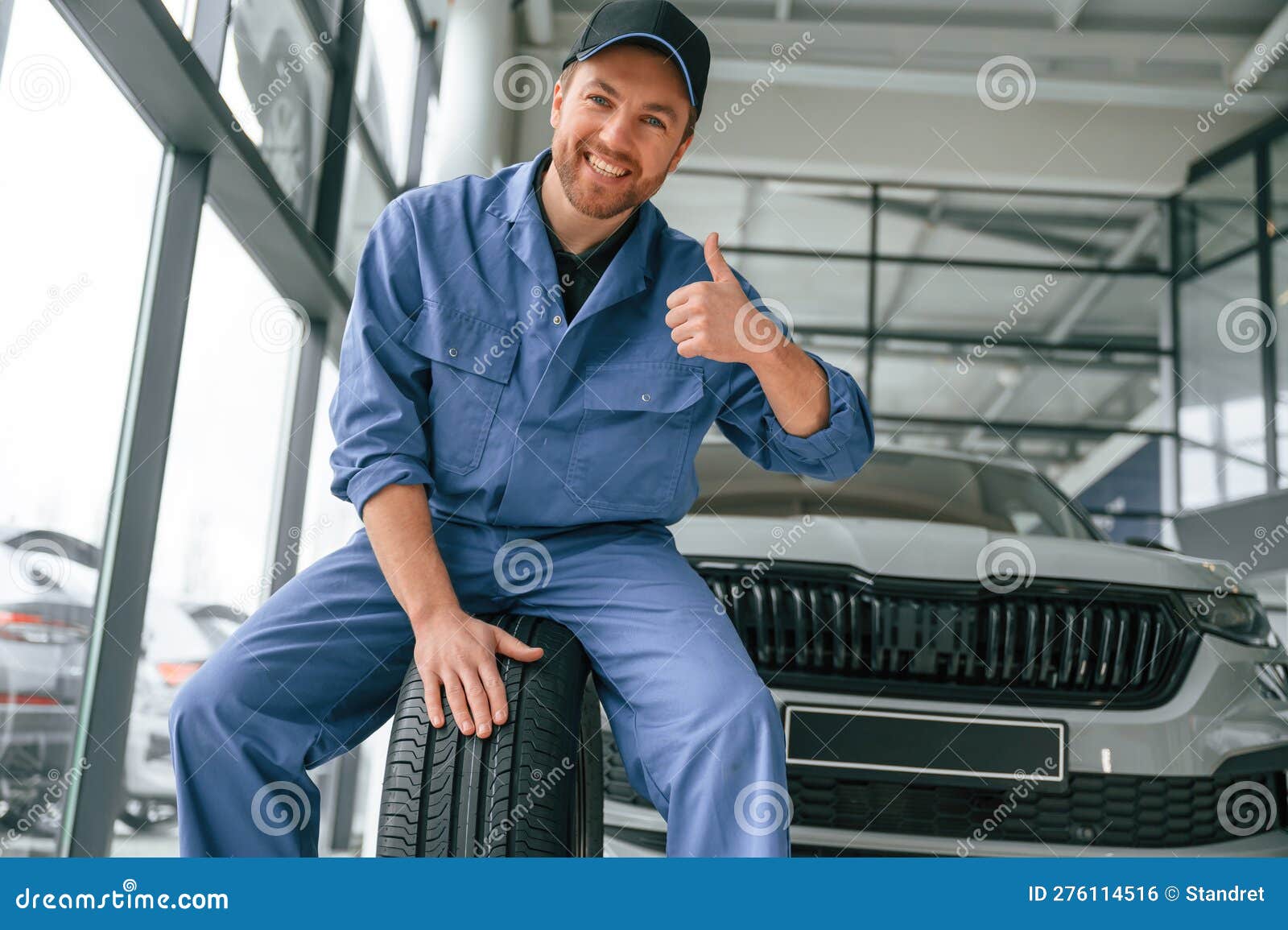 Having Fun, Smiling, with Tire. Man in Blue Uniform is Working in the