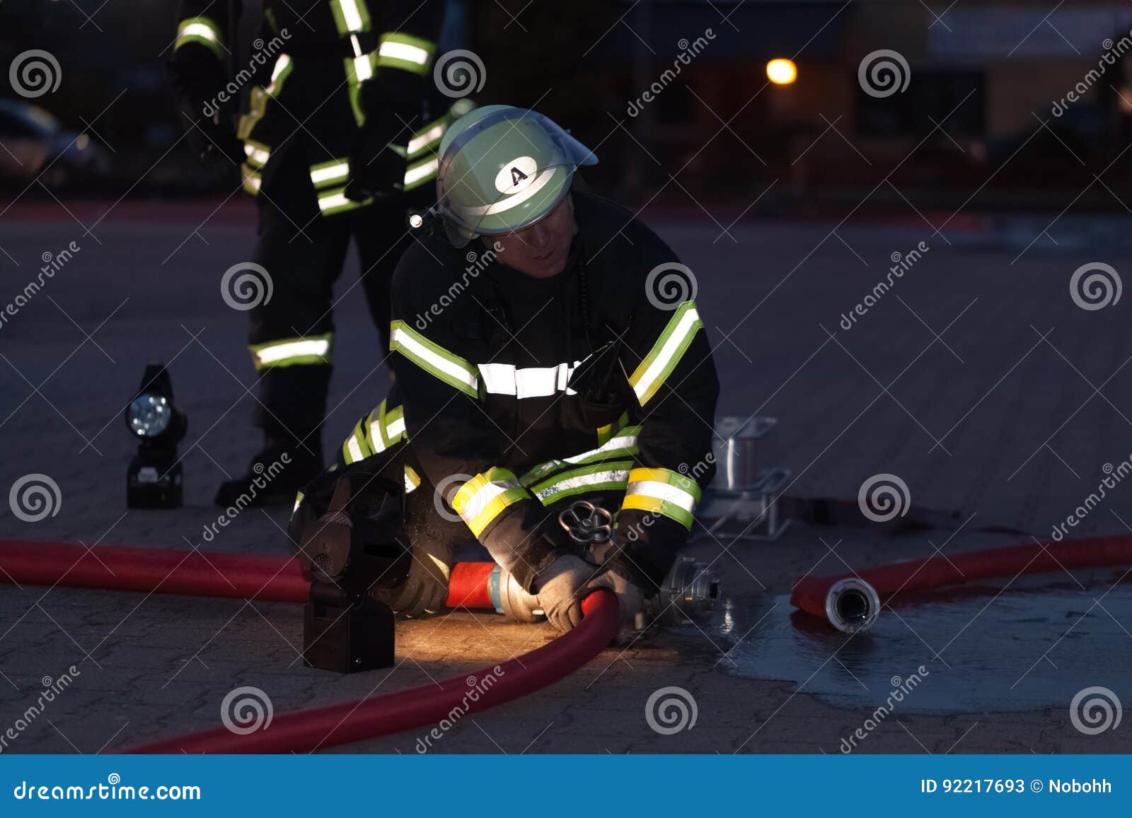 HDR Firefighter in Action with a Fire Hose in the Evening Editorial