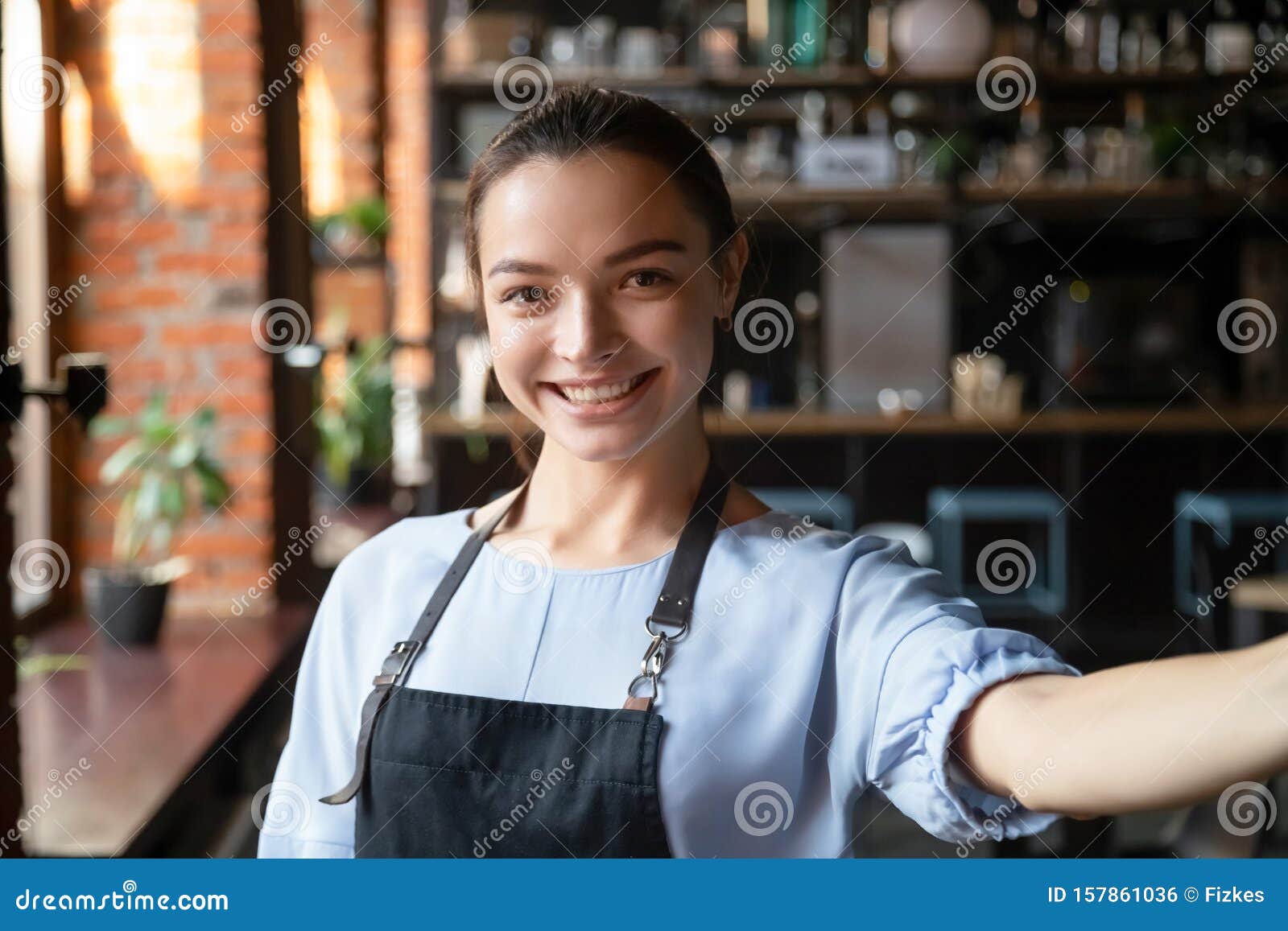 head shot portrait of attractive smiling waitress in cozy coffeehouse