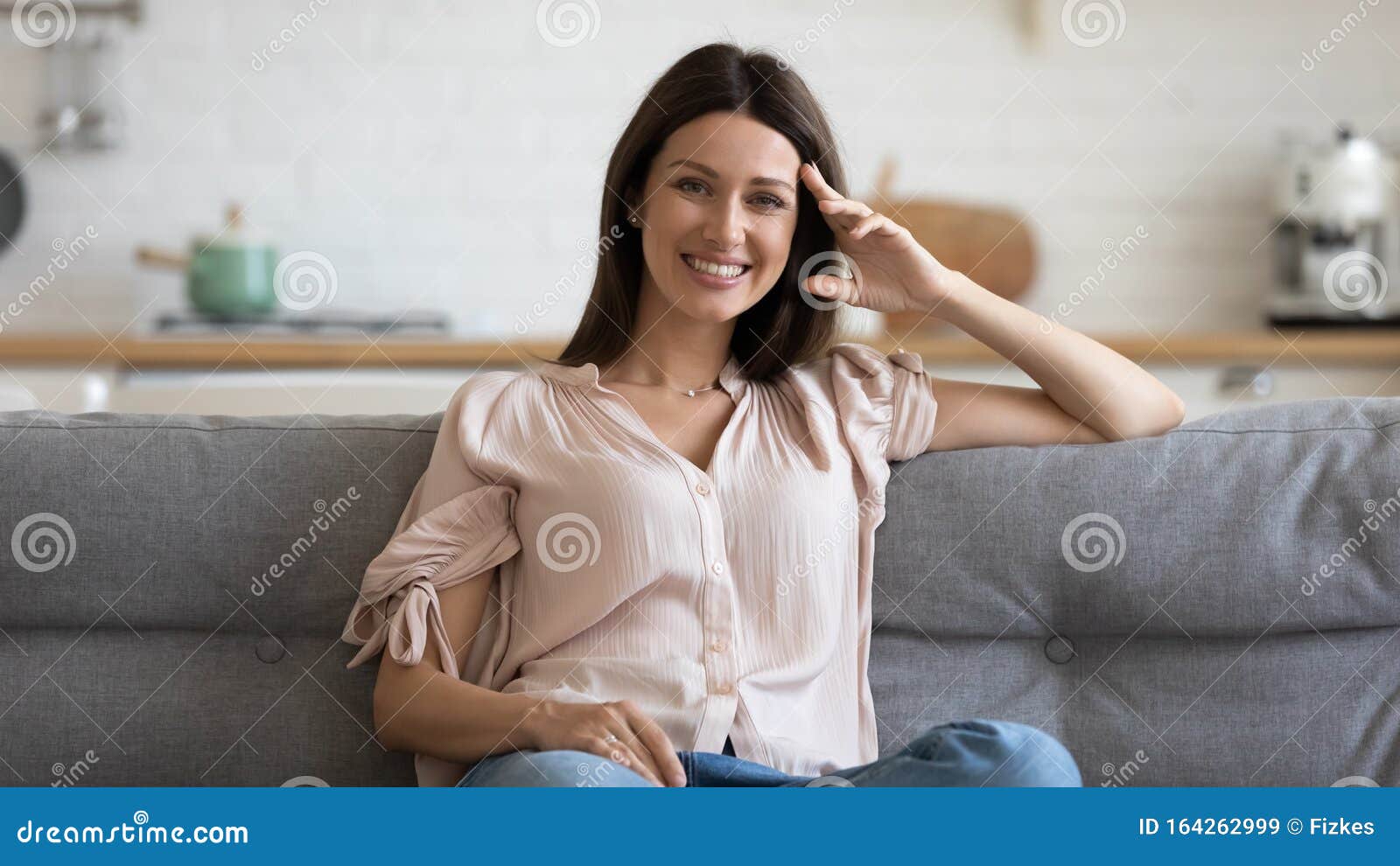 happy 30s woman sitting on cozy sofa in living room.