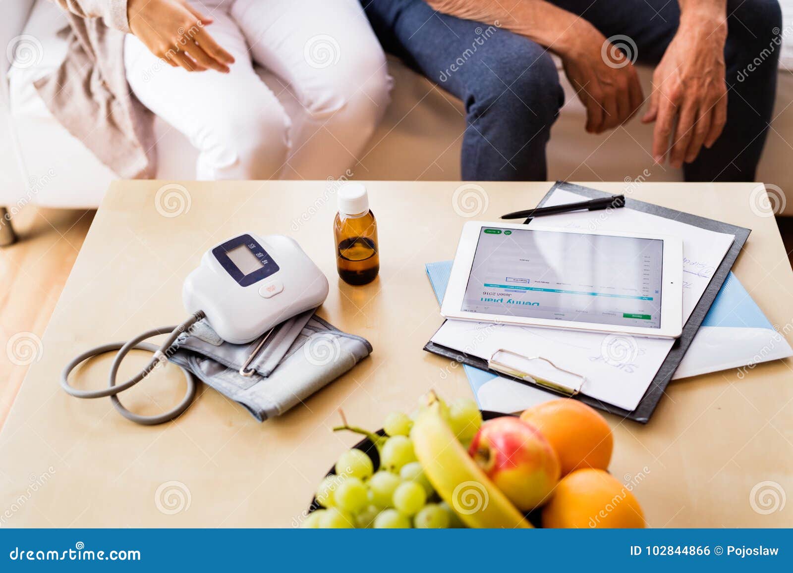 health visitor and a senior man with tablet during home visit.