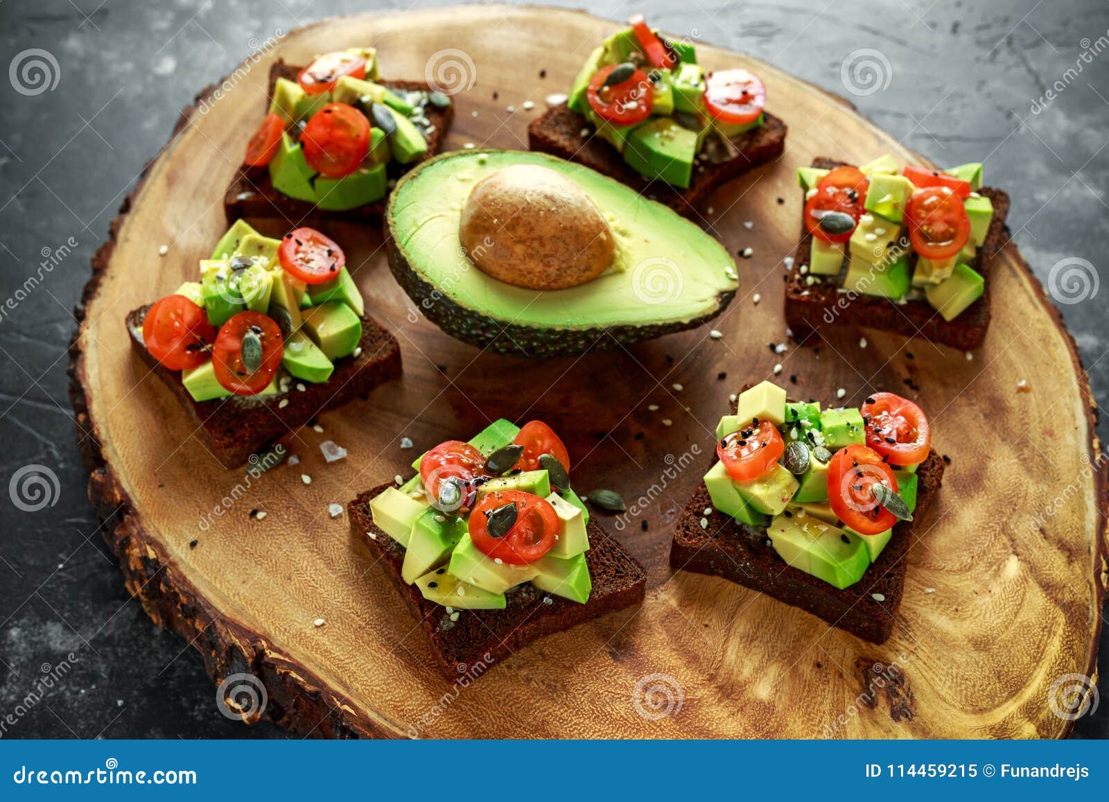 healthy avocado and cherry tomato rye sourdough toasts with pumpkin, sesame and nigella seeds, drizzled with olive oil