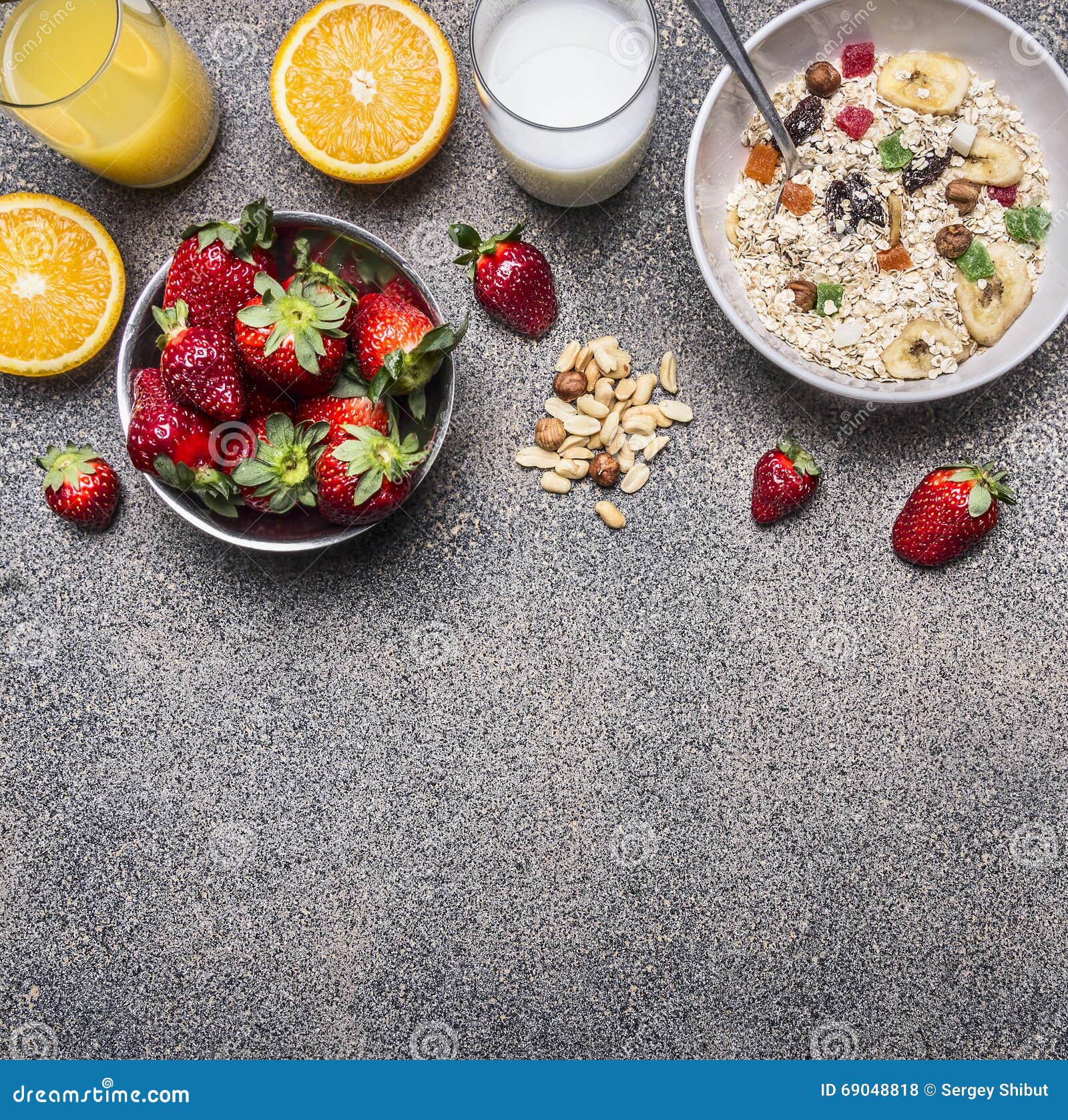 healthy breakfast cereal with dried fruits, fresh orange juice, a plate of strawberries on wooden rustic background top view borde