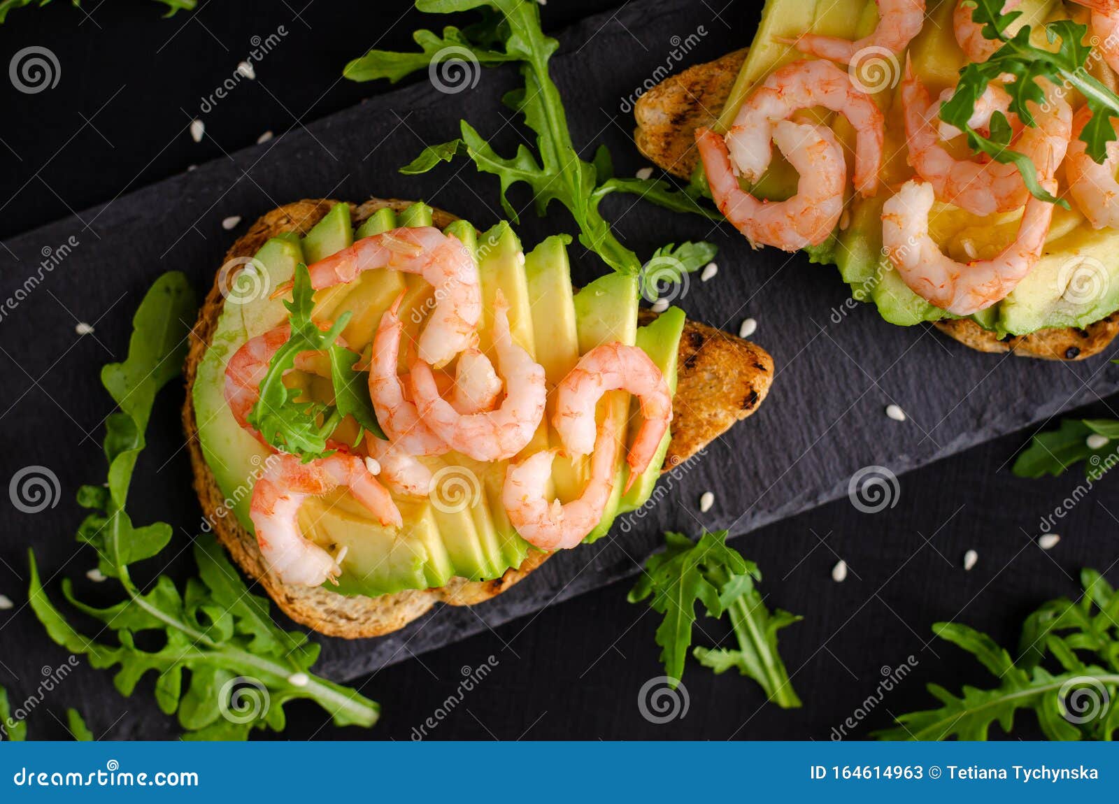 Healthy Food Concept. Toasts with Avocado, Shrimps and Arugula on Black ...