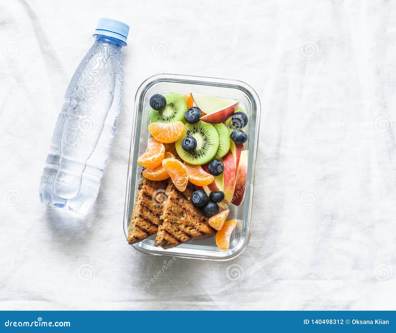 healthy food snack sweet vitamin lunch box and bottle of clean water on a light background. peanut butter toast, apples