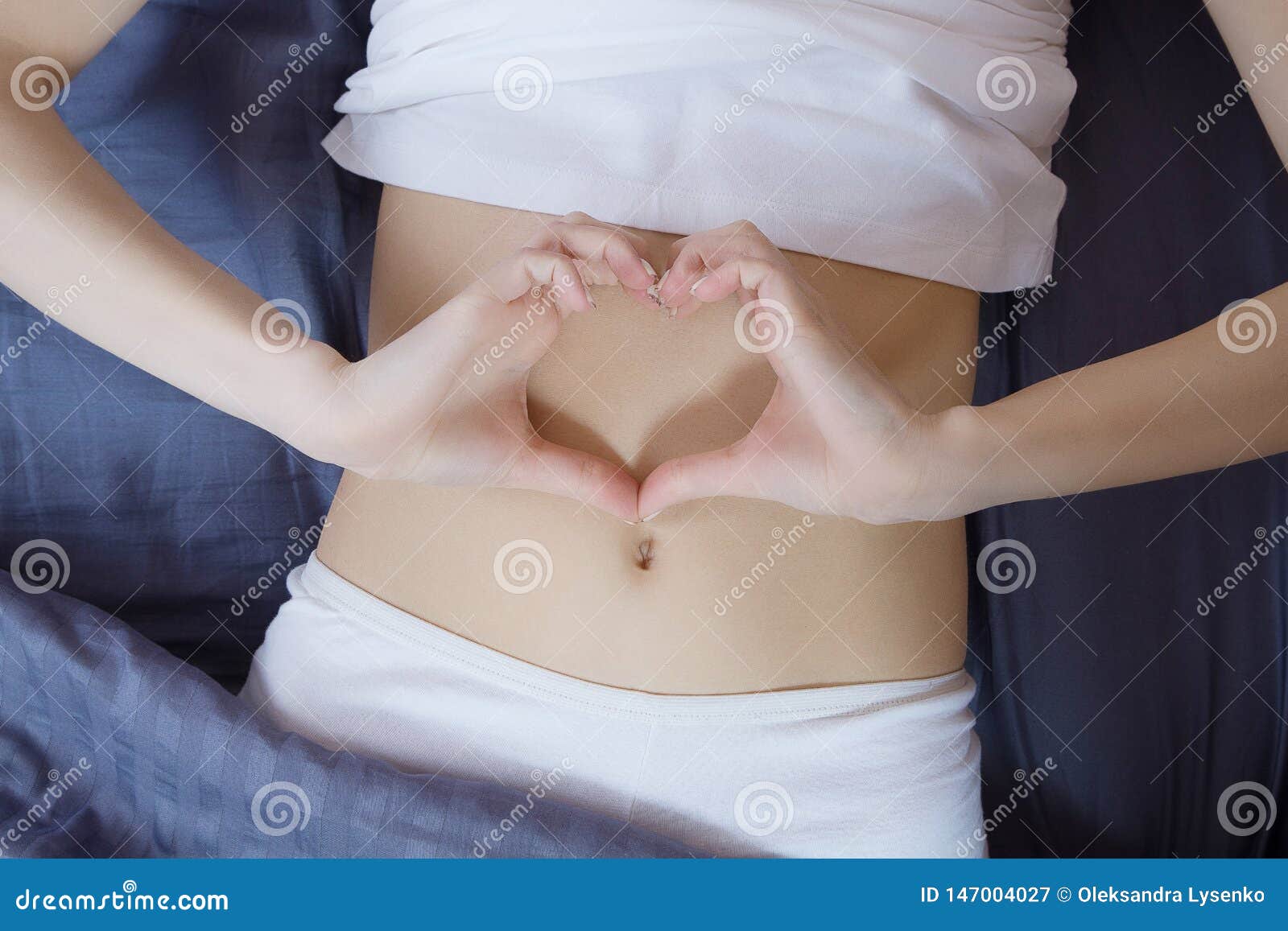 healthy nutrition and belly health concept. close up of woman flat stomach. girl in bed with hungry feeling. top view
