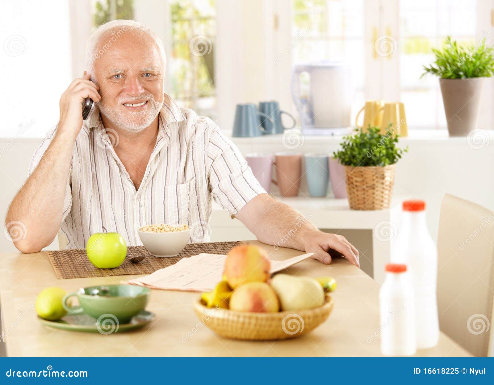 healthy pensioner using cellphone at breakfast