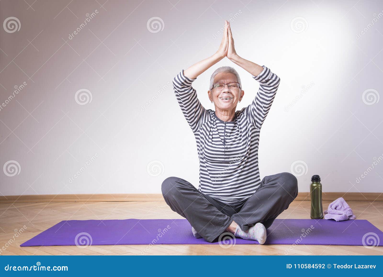 Active grandma using resistance band sitting on yoga mat at home