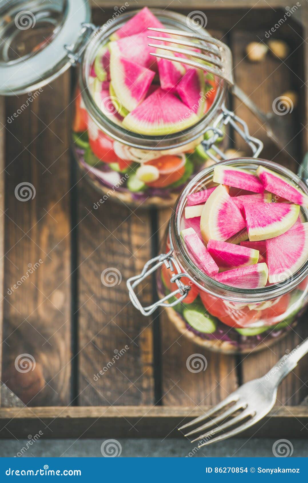 healthy vegetarian salad in jars over wooden tray background