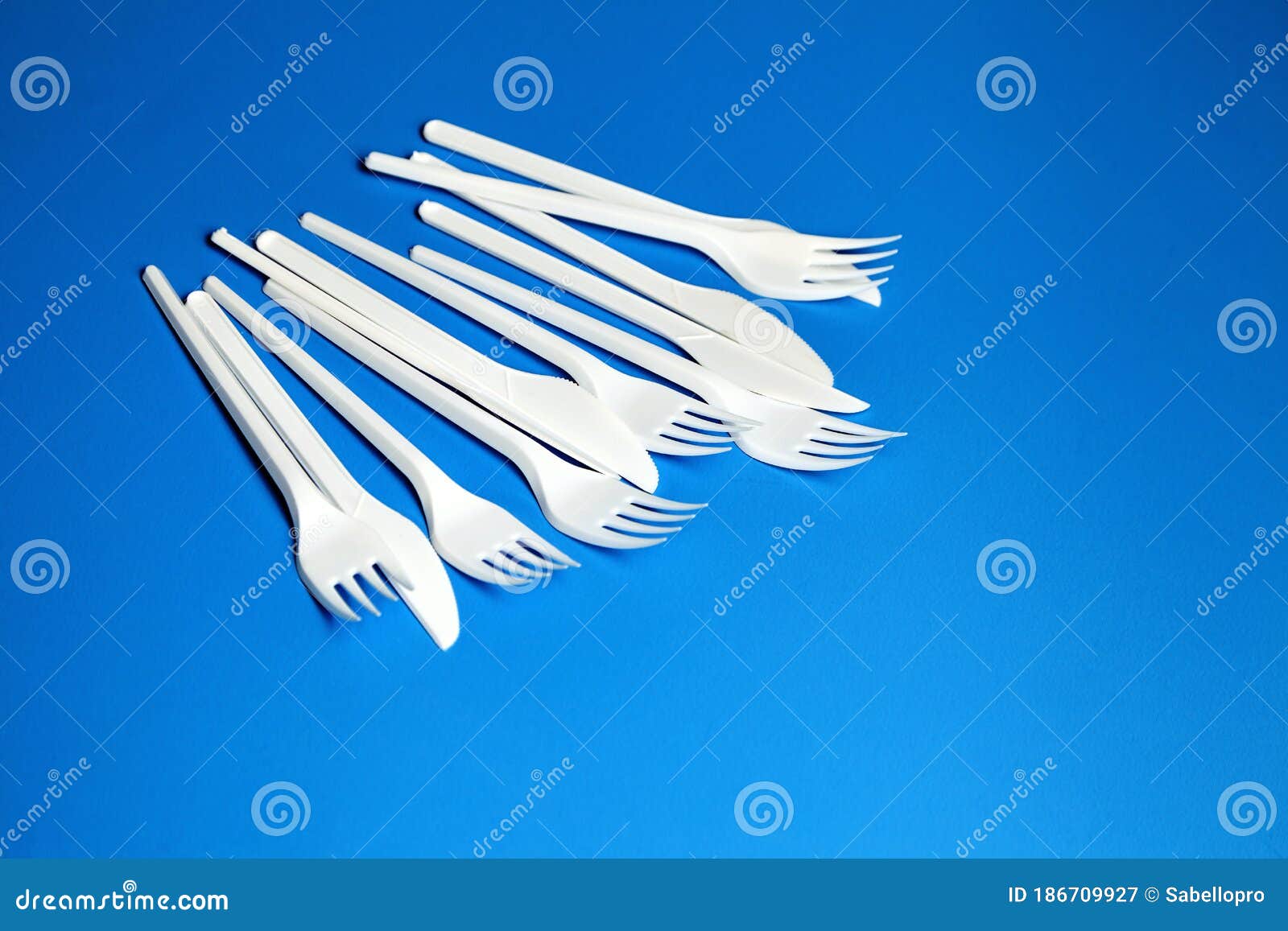White Plastic Knives and Forks. Disposable Plastic Tableware on Blue