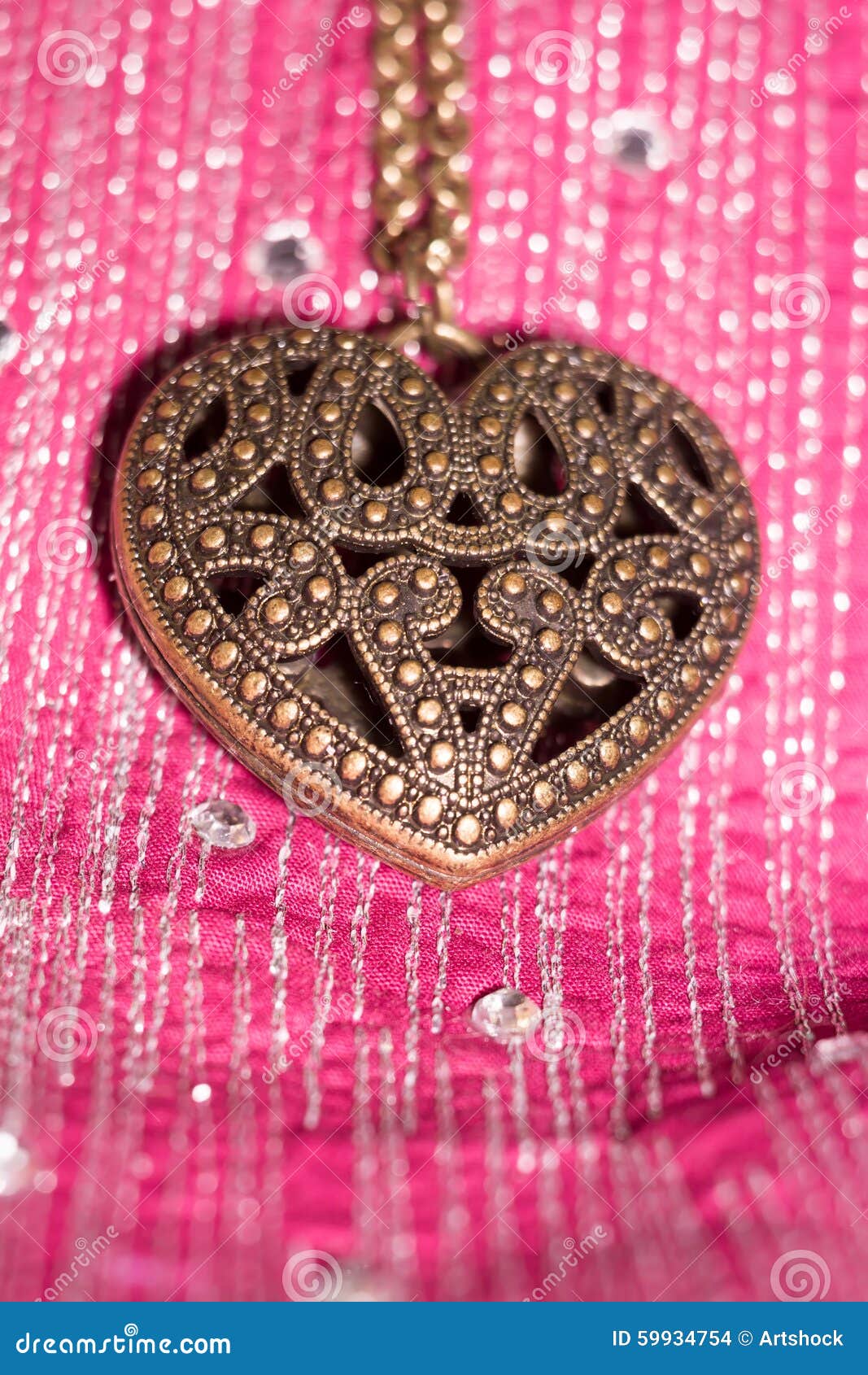 Heart Pendant on Silk. Vintage big heart shaped pendant on silk fabric background.