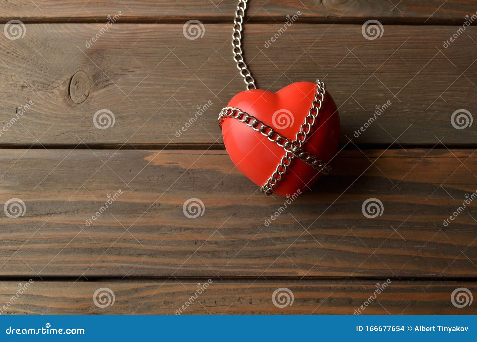 Heart And Secured With The Chain. Heart In Chains On A Dark Wooden