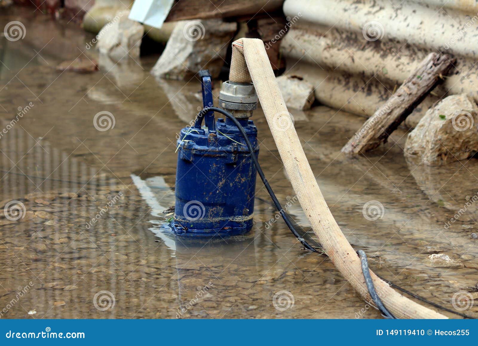 Heavily Used Old Partially Submerged Metal Water Pump Pumping Water From Flooded Backyard Through Fire Hose Surrounded With Rocks Stock Photo Image Of Water