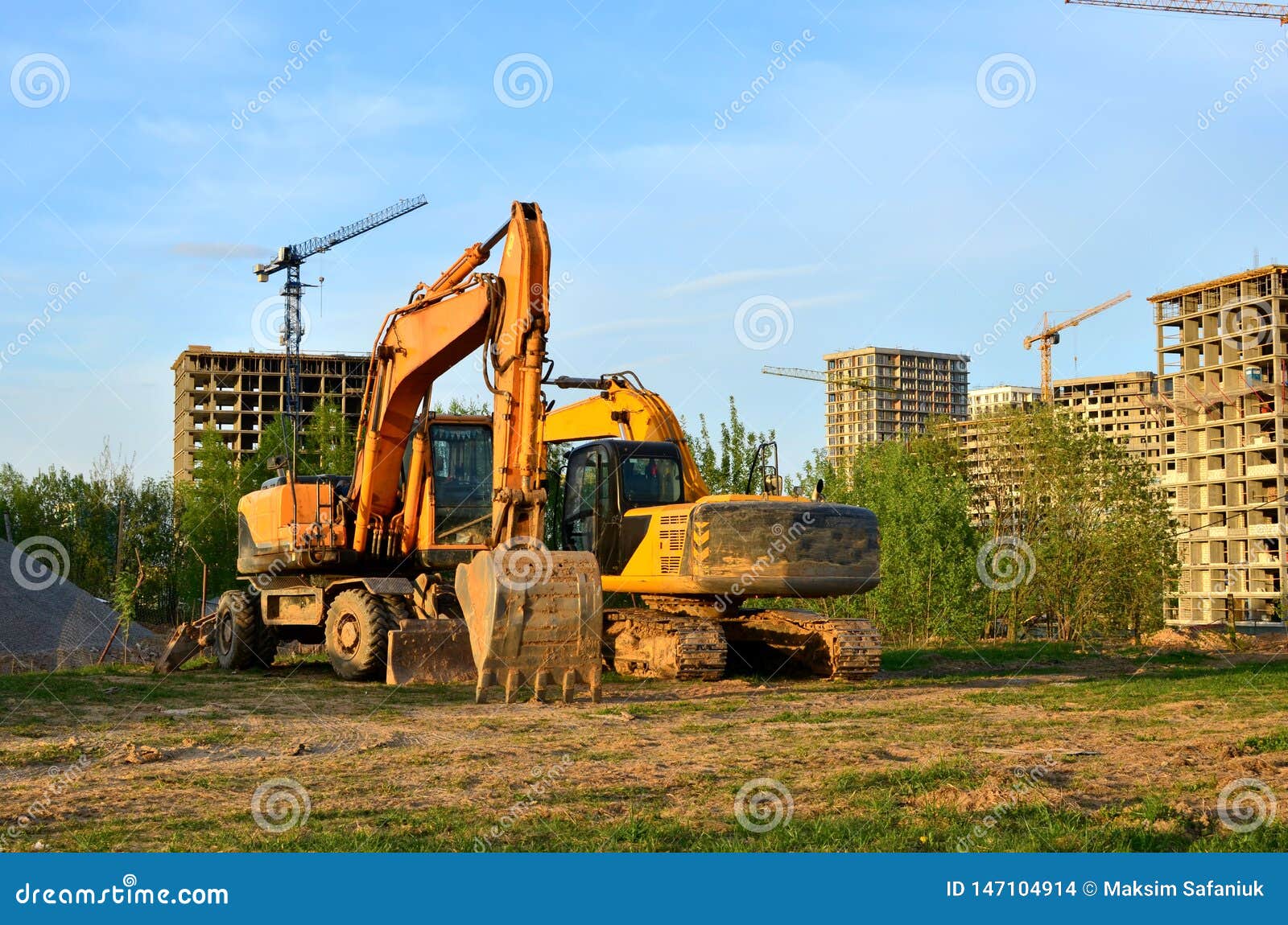 Heavy Tracked Excavator at a Construction Site on a Background of a  Residential Building and Construction Cranes on a Sunny Day Stock Photo -  Image of excavator, build: 147104914