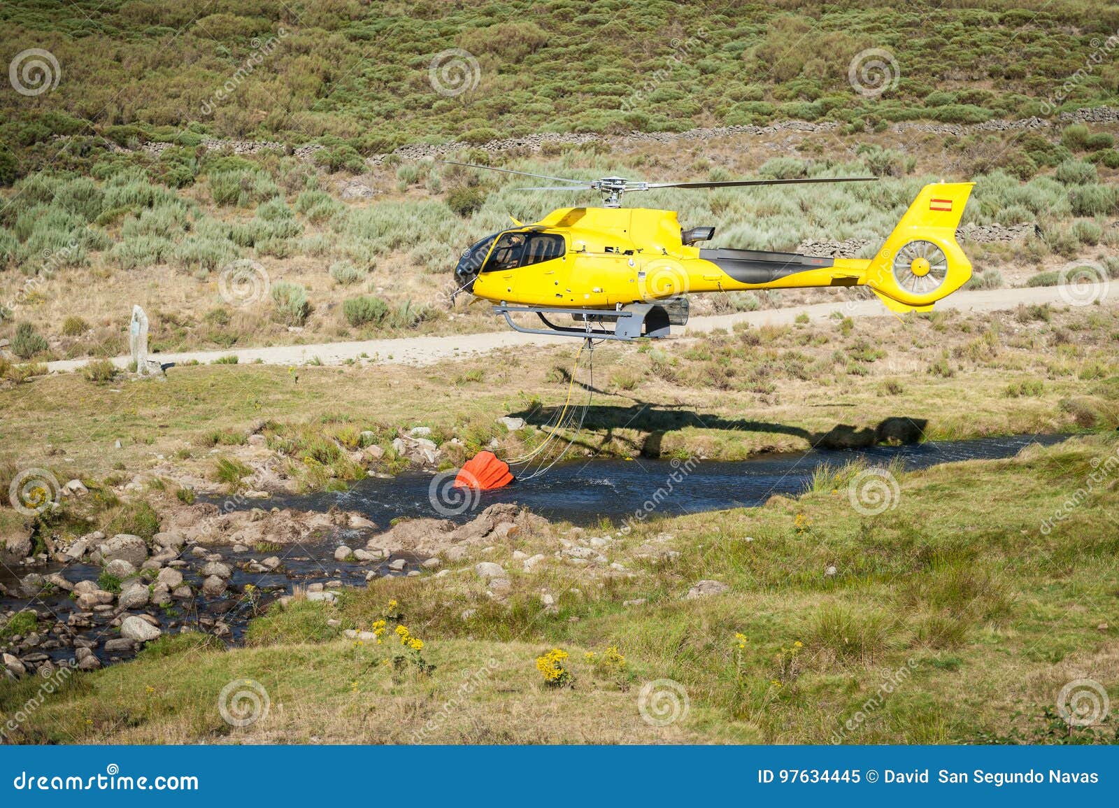 Helicopter Firefighters Picking Up Water from Small River Stock Image