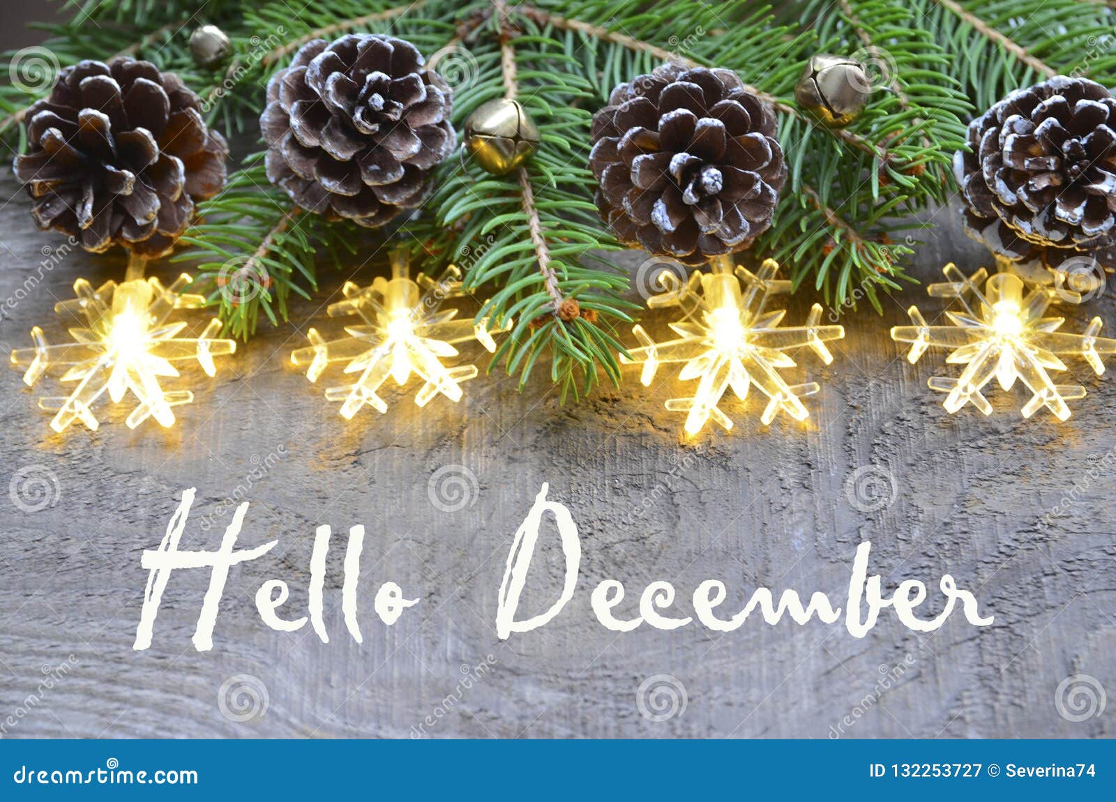 hello december.christmas decoration with fir tree,pine cones and garland lights on old wooden background.
