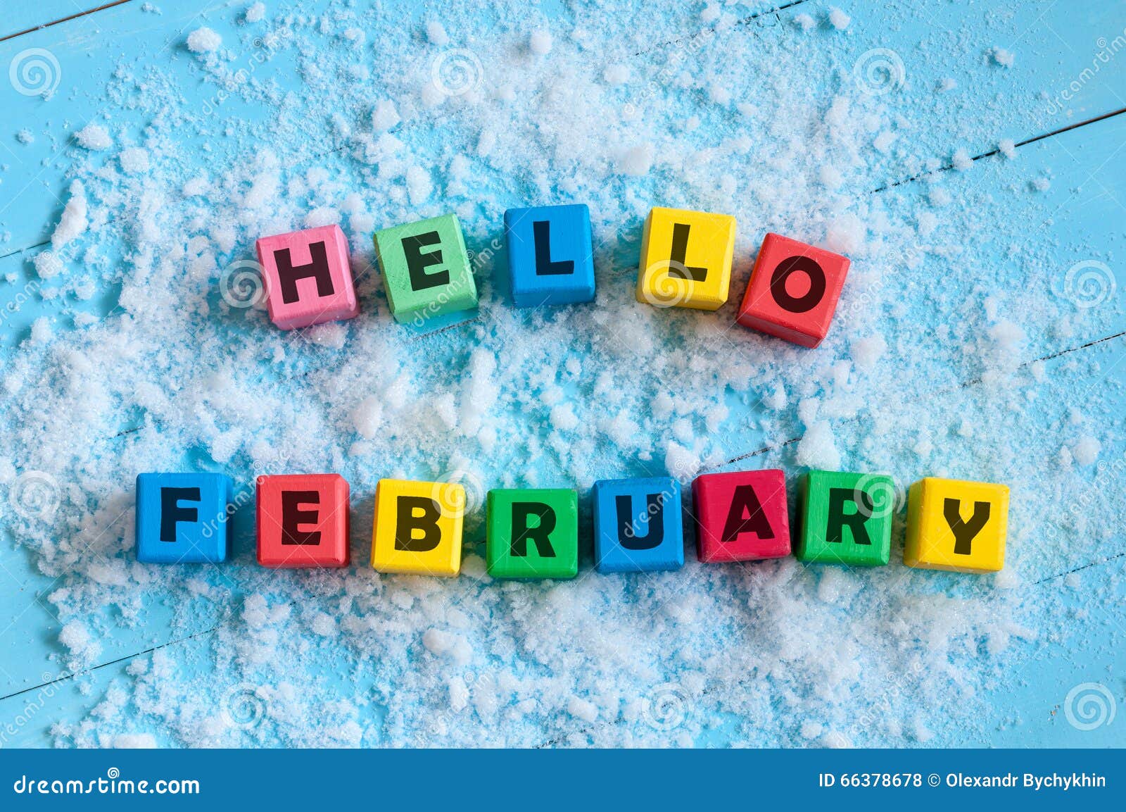 hello february written on colour wooden toy cubes on light background with snow