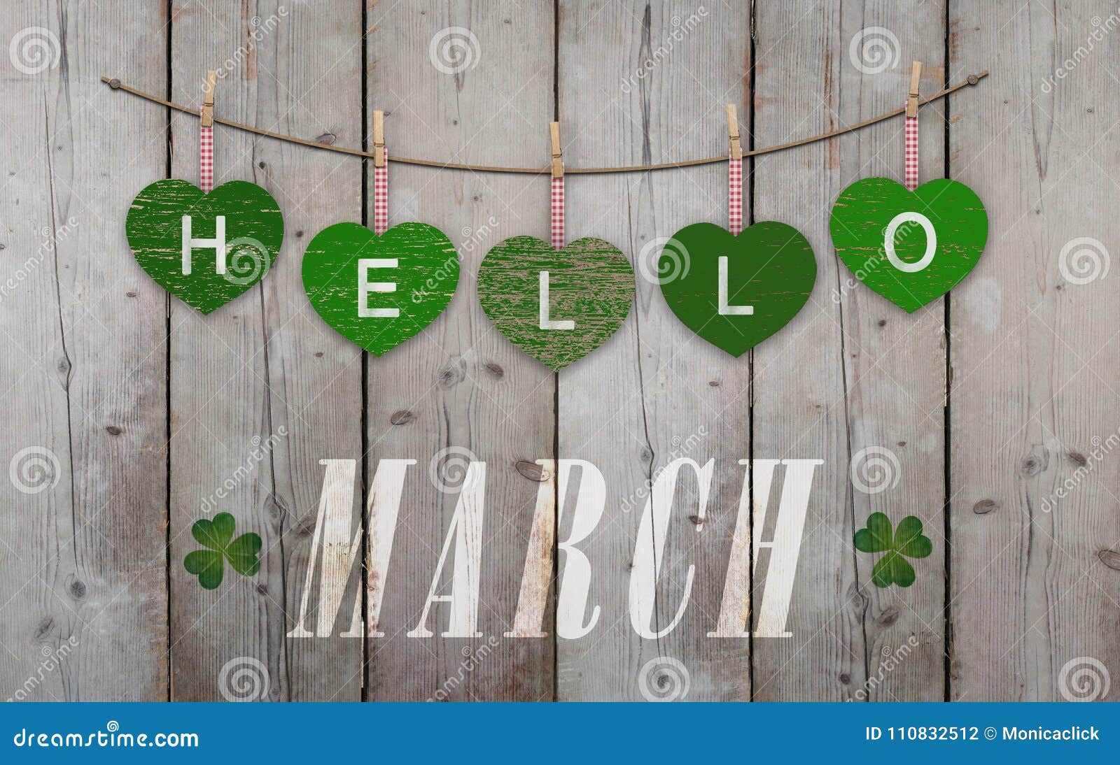 Hello March written on hanging green hearts and weathered wooden background