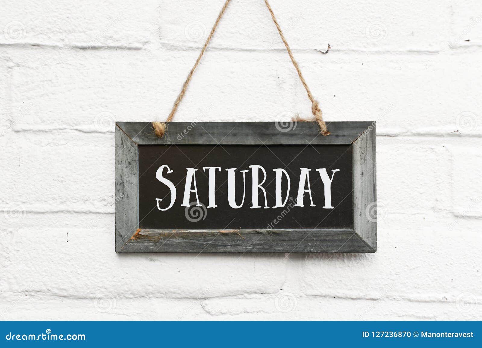 hello saturday text on hanging board white brick outdoor wall