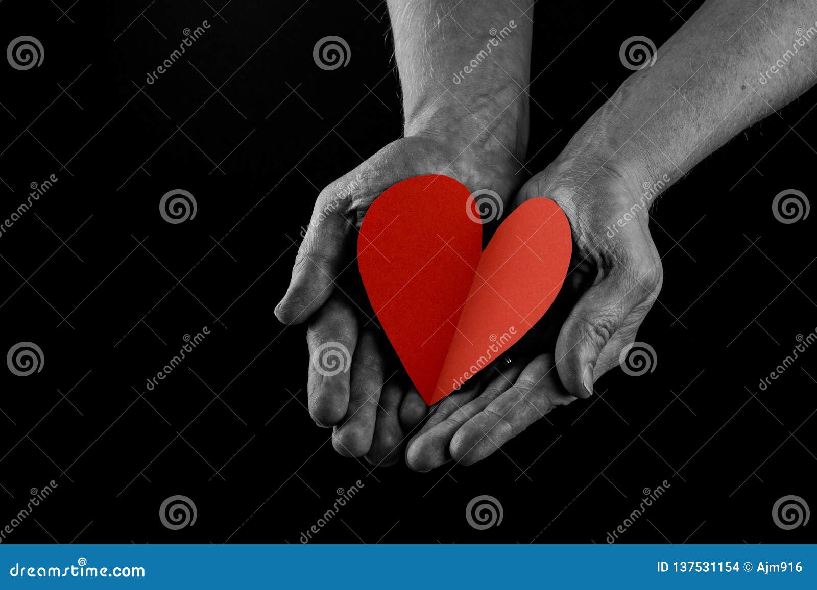 helping hand concept, man`s hands palms up holding a red heart, giving love, care and support, reaching out. side view