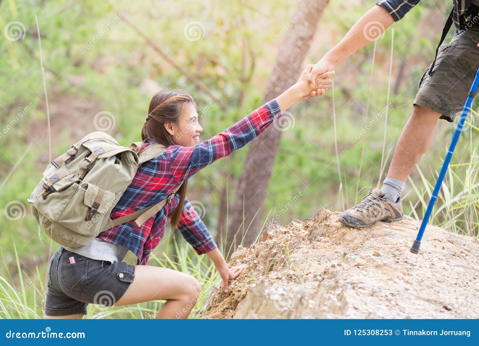 helping hand - hiker woman getting help on hike smiling happy overcoming obstacle. tourist walking on the mountain, young couple