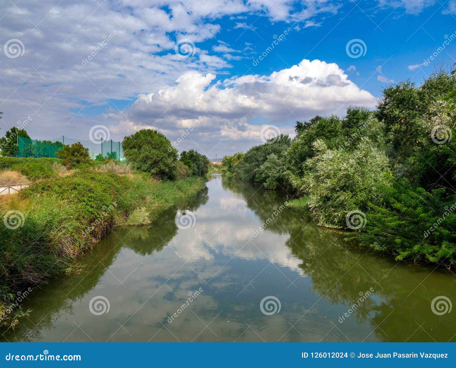 henares river on its way through the city of alcala de henares in spain with very green banks