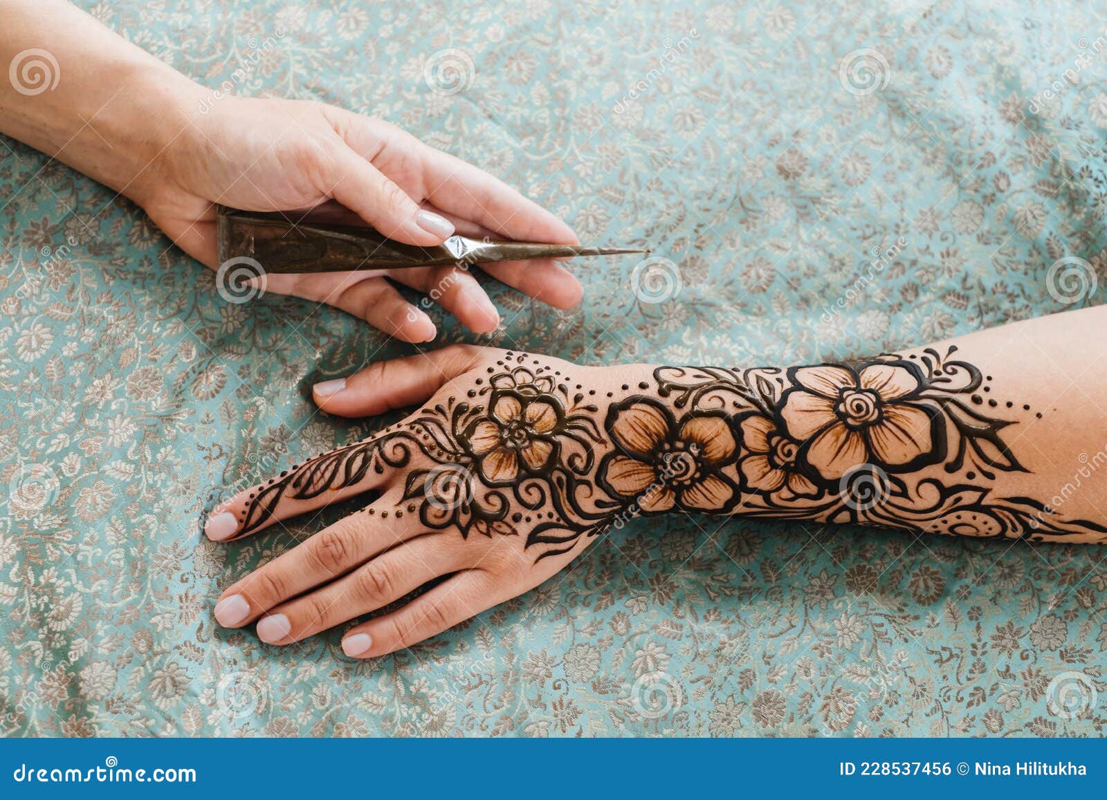 Artista aplicando tatuagem de henna mehndi na mão feminina