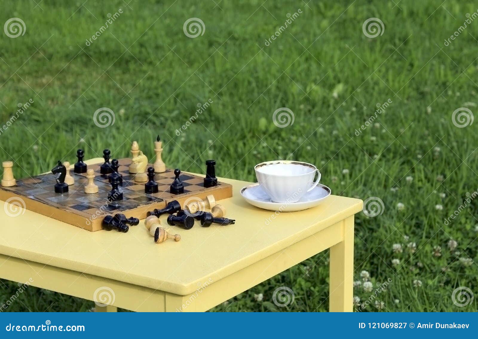 Herbaciany przyjęcie na naturze Gra szachy outdoors. Bawić się szachy z herbatą na żółtym stole outdoors w świeżym powietrzu