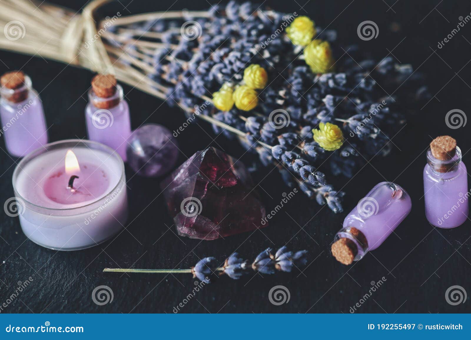 herbal magick in wicca and witchcraft using lavender infused water. purple candle, amethyst pyramid crystal, dried lavender flower