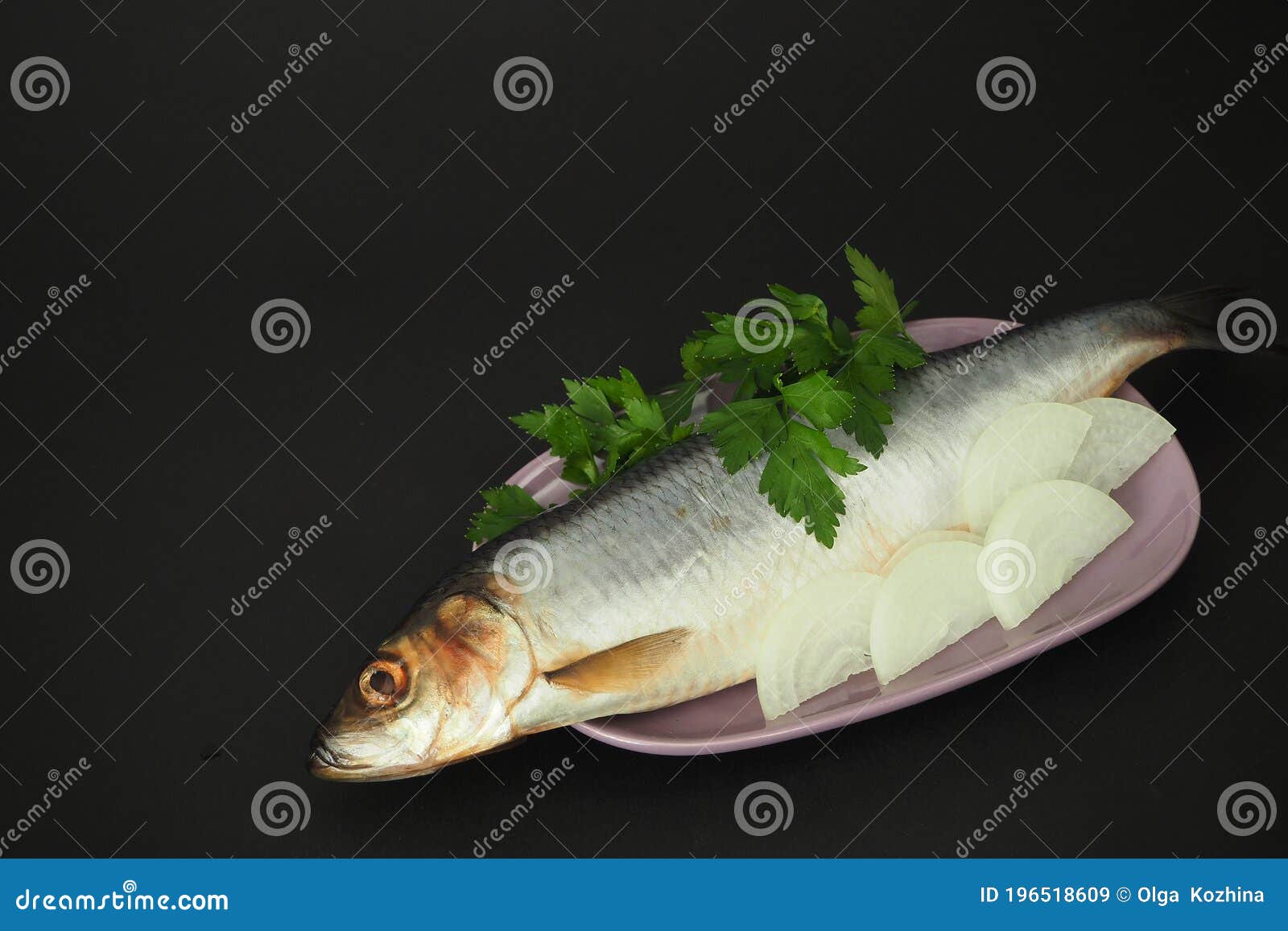herring is whole, undivided with onion and parsley close-up.