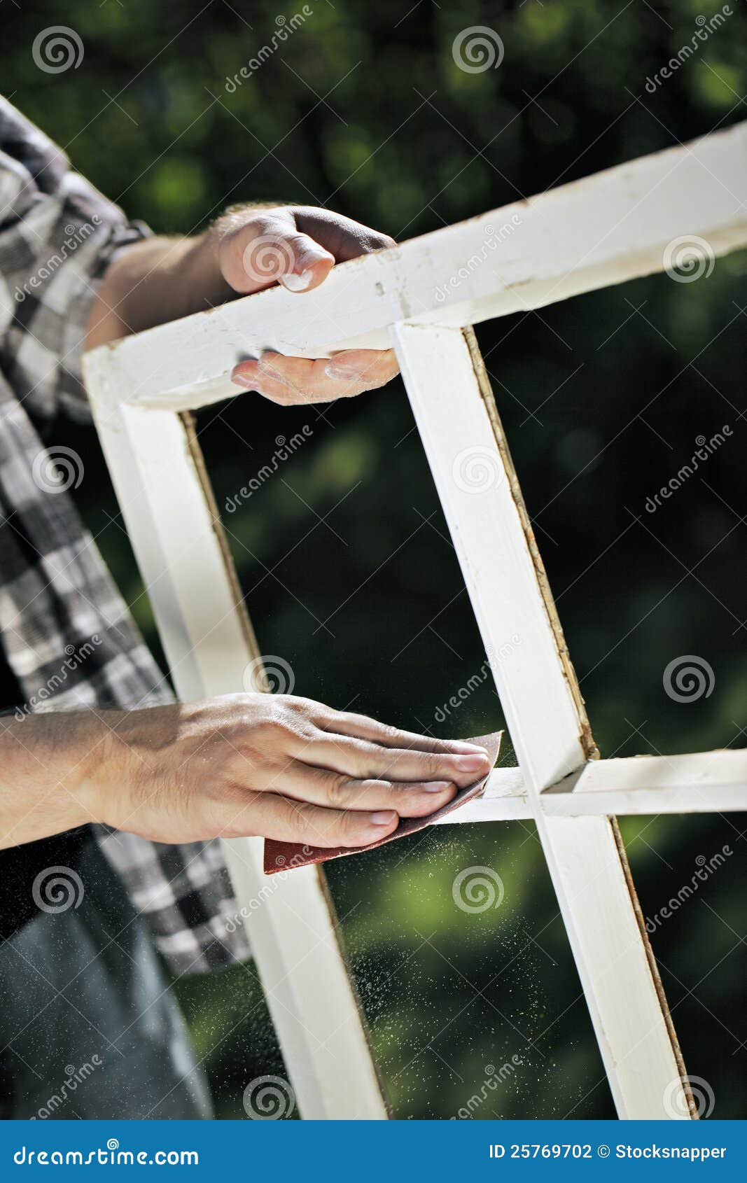Het bevestigen van de vensters. Mens die een stuk van schurend schuurpapier op een oud raamkozijn gebruikt.