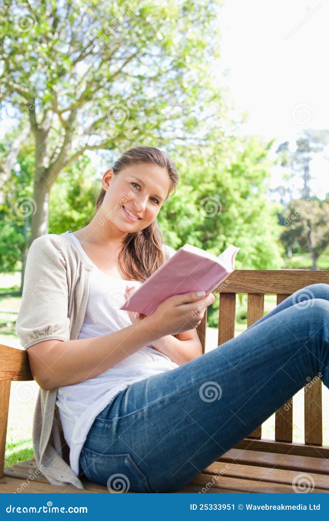 Сидящая женщина с книгой. Девушка сидит и читает на скамейке. Девушка с книжкой в руках на скамейке. Женщина сидит на улице и улыбается. Женщина сидит и читает книгу.