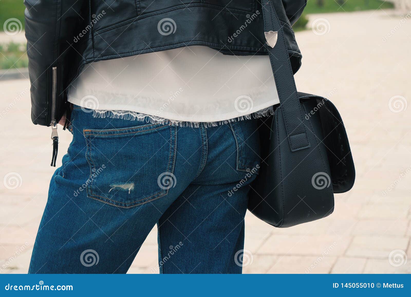 Het jonge vrouw stellen in jeans met zwarte handtas achtermening