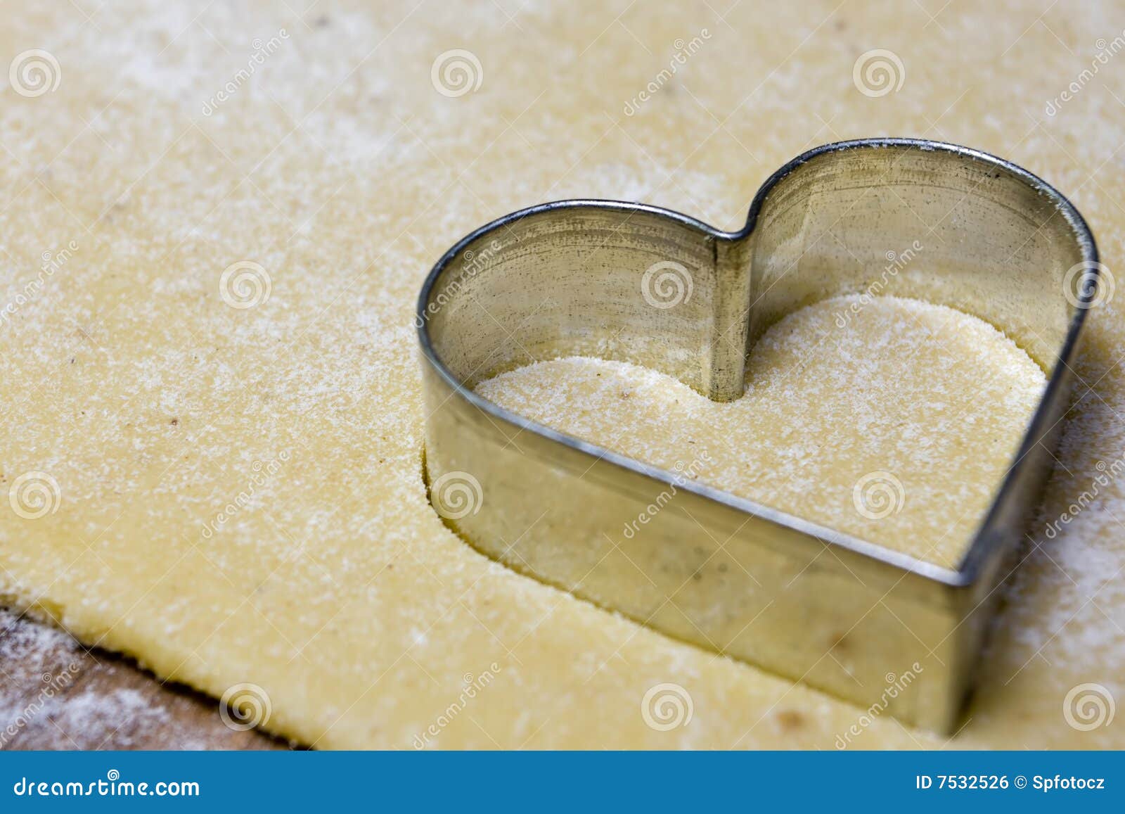 Het koekjessnijder van het hart op een blad van koekjesdeeg