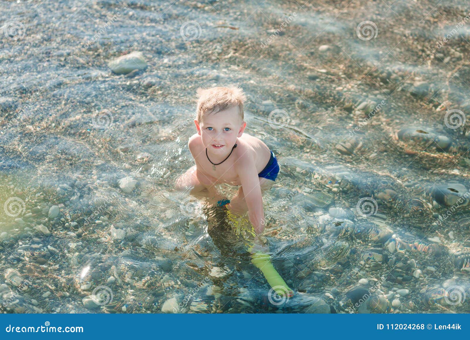 Het leuke gelukkige jong geitje spelen met waterpistool bij de kust