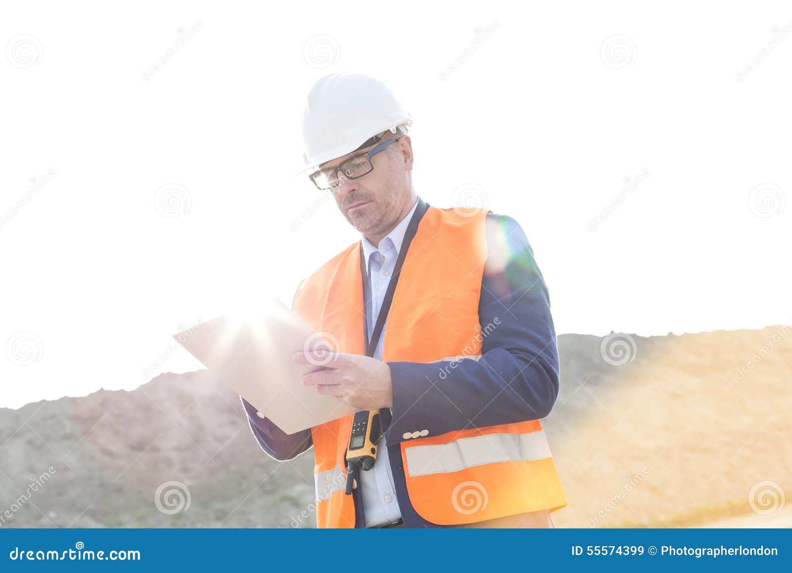 Het mannelijke klembord van de supervisorlezing bij bouwwerf op zonnige dag