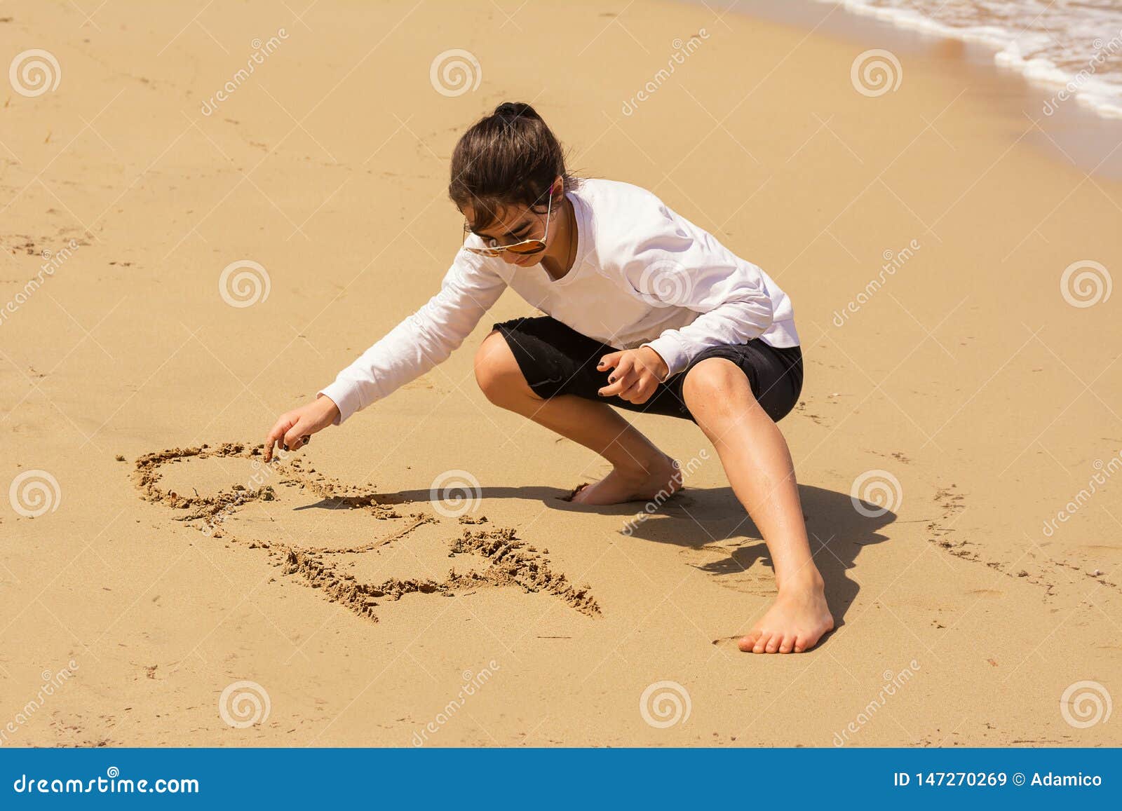 Het meisje trekt I-liefde op het zand. Een weinig trekt het meisje I-liefde op het zand